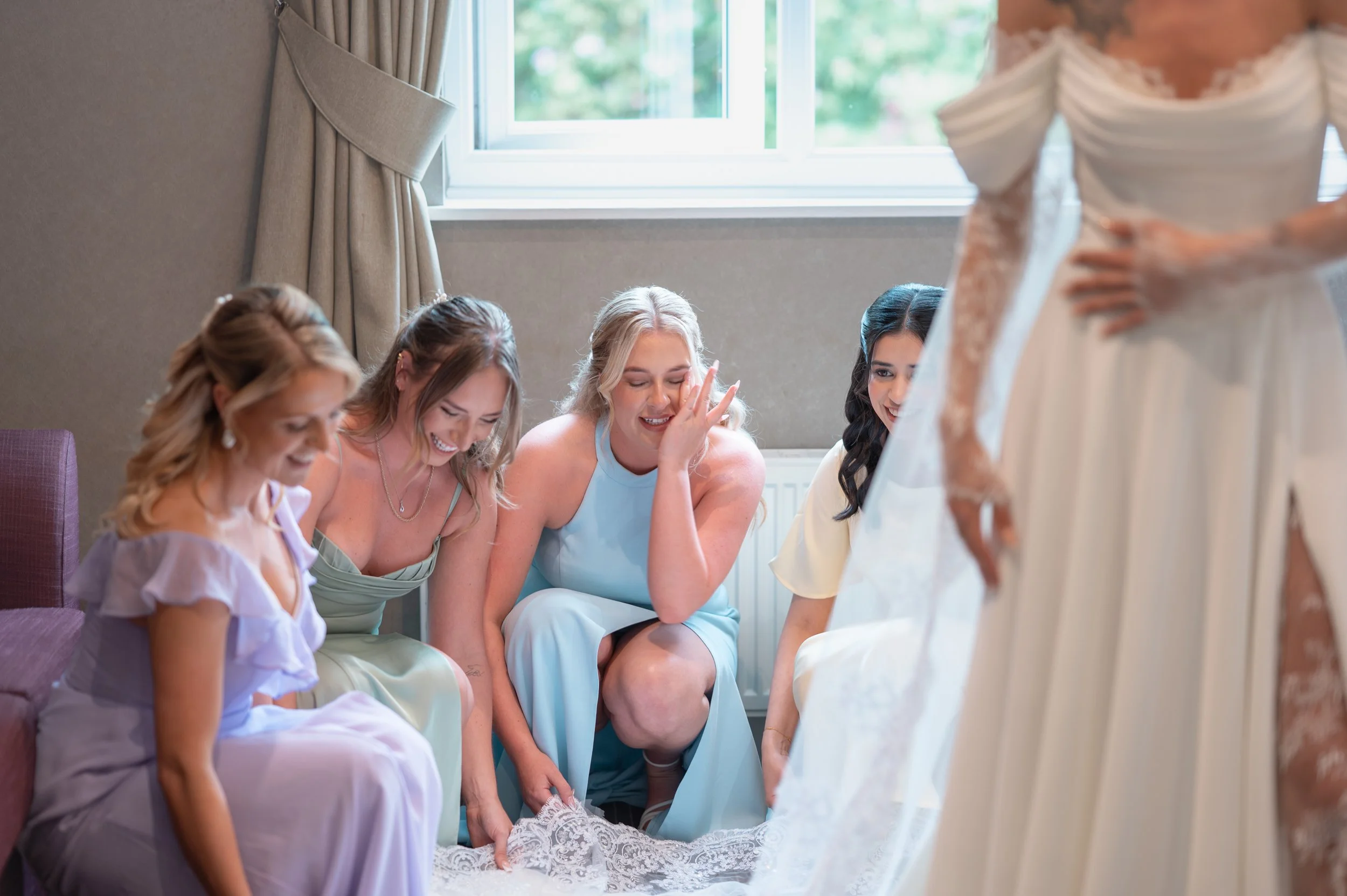 A group of women sitting together, happily looking at a wedding dress.