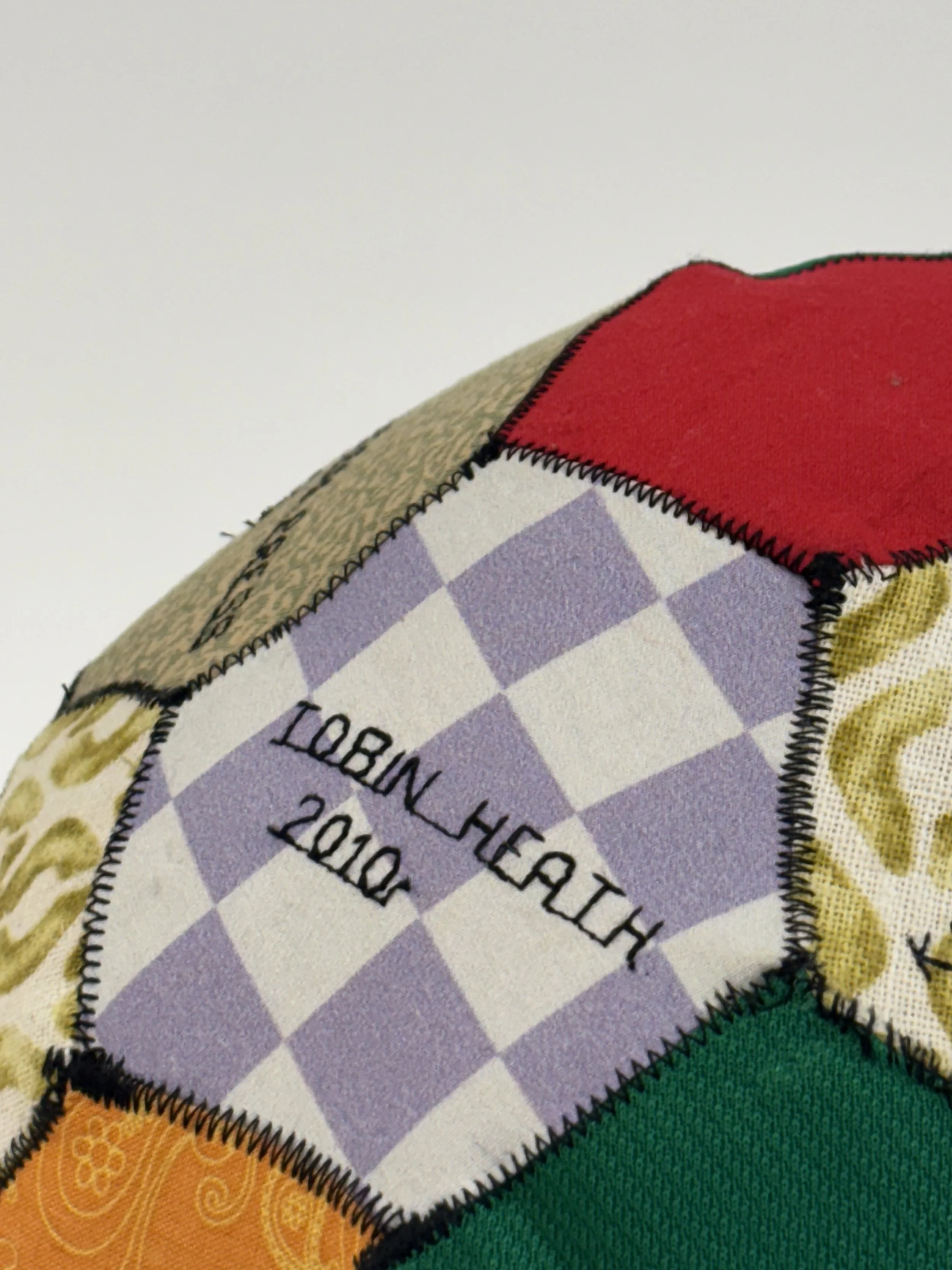 Alexis Fredericks, UNITED., hand-stitched patchwork soccer ball embroidered with the names of queer National Women's Soccer League athletes, exploring collective memory and belonging