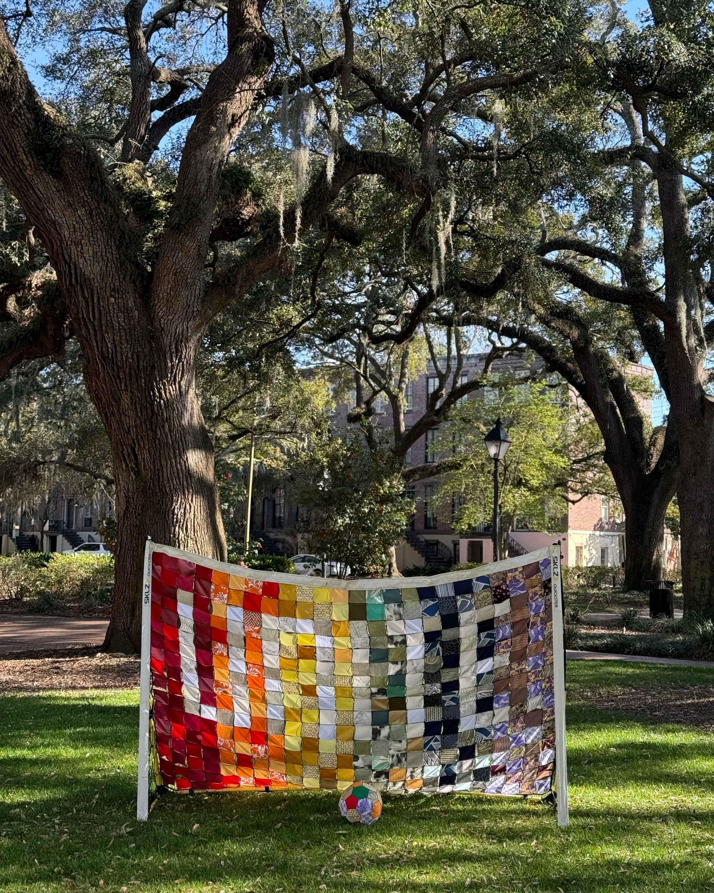Alexis Fredericks, UNITE., patchwork soccer net installation exploring queer identity, collective belonging, and visibility in women's sports. UNITED., patchwork quilted soccer ball, embroidered with the names of NWSL queer players.