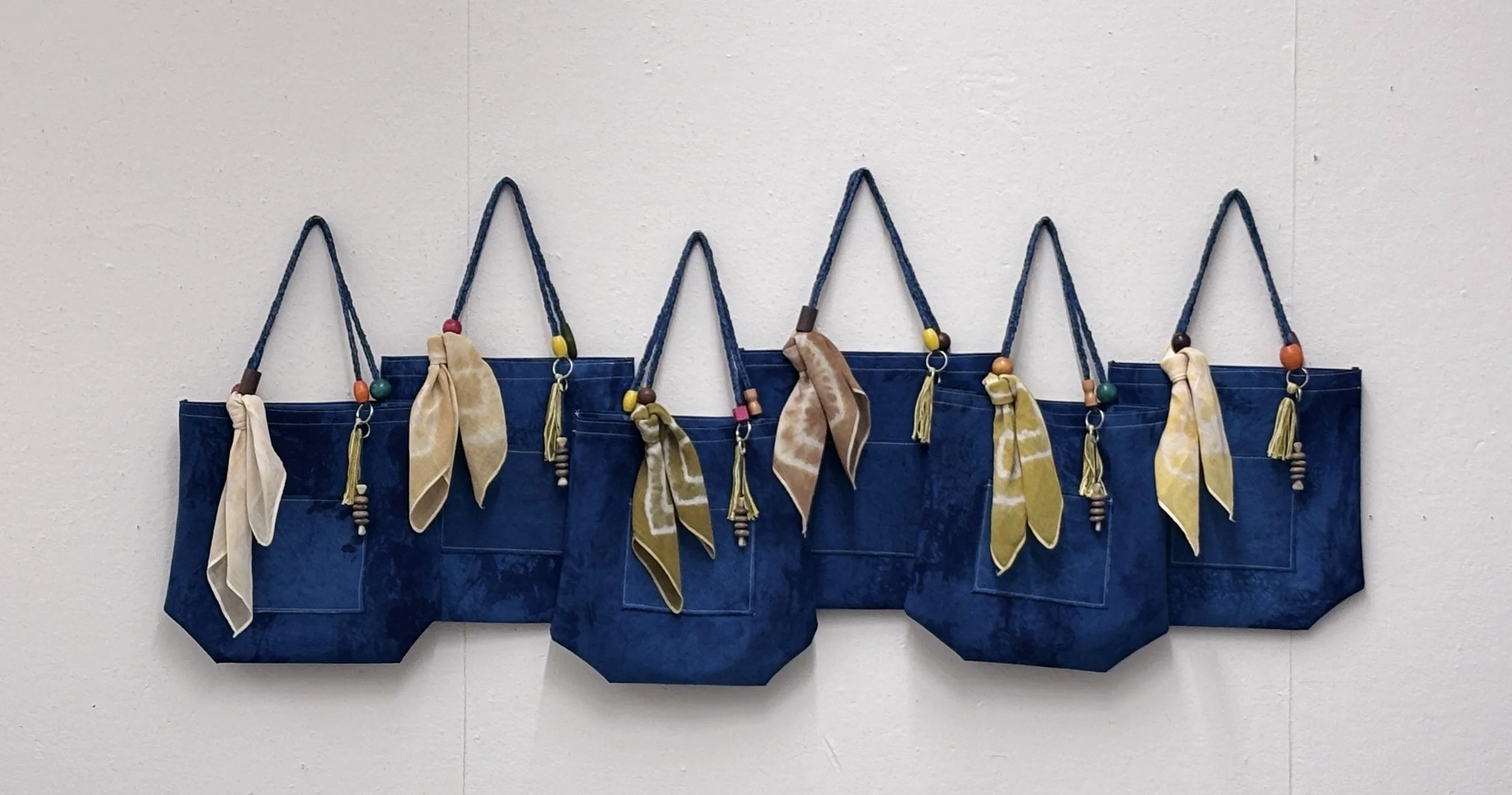 Alexis Fredericks, WORKING CLOTH., six handcrafted textile bags displayed as an installation, exploring the relationship between institutional affiliation, artistic labor, and professional recognition.
