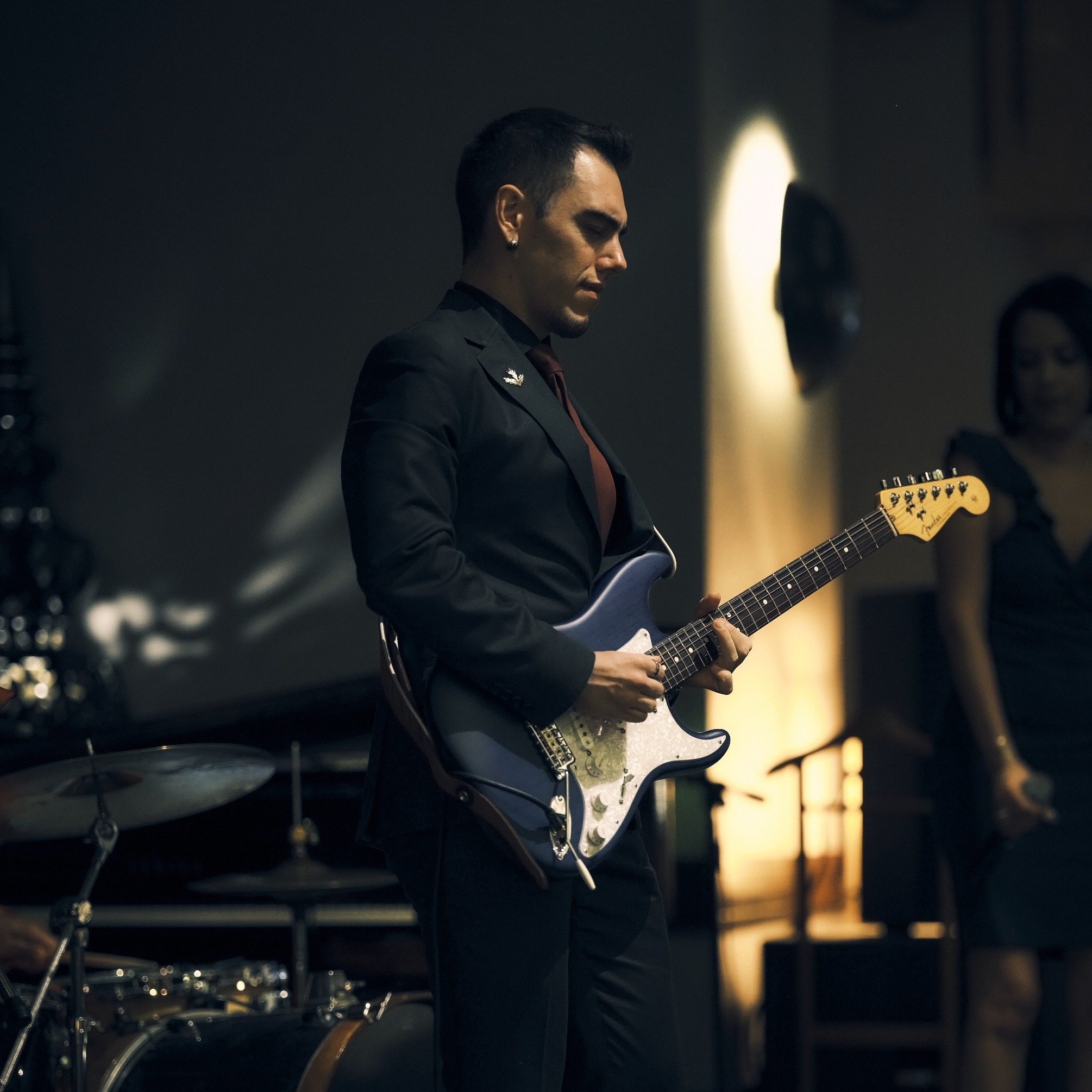 A person playing an electric guitar in a dimly lit room.
