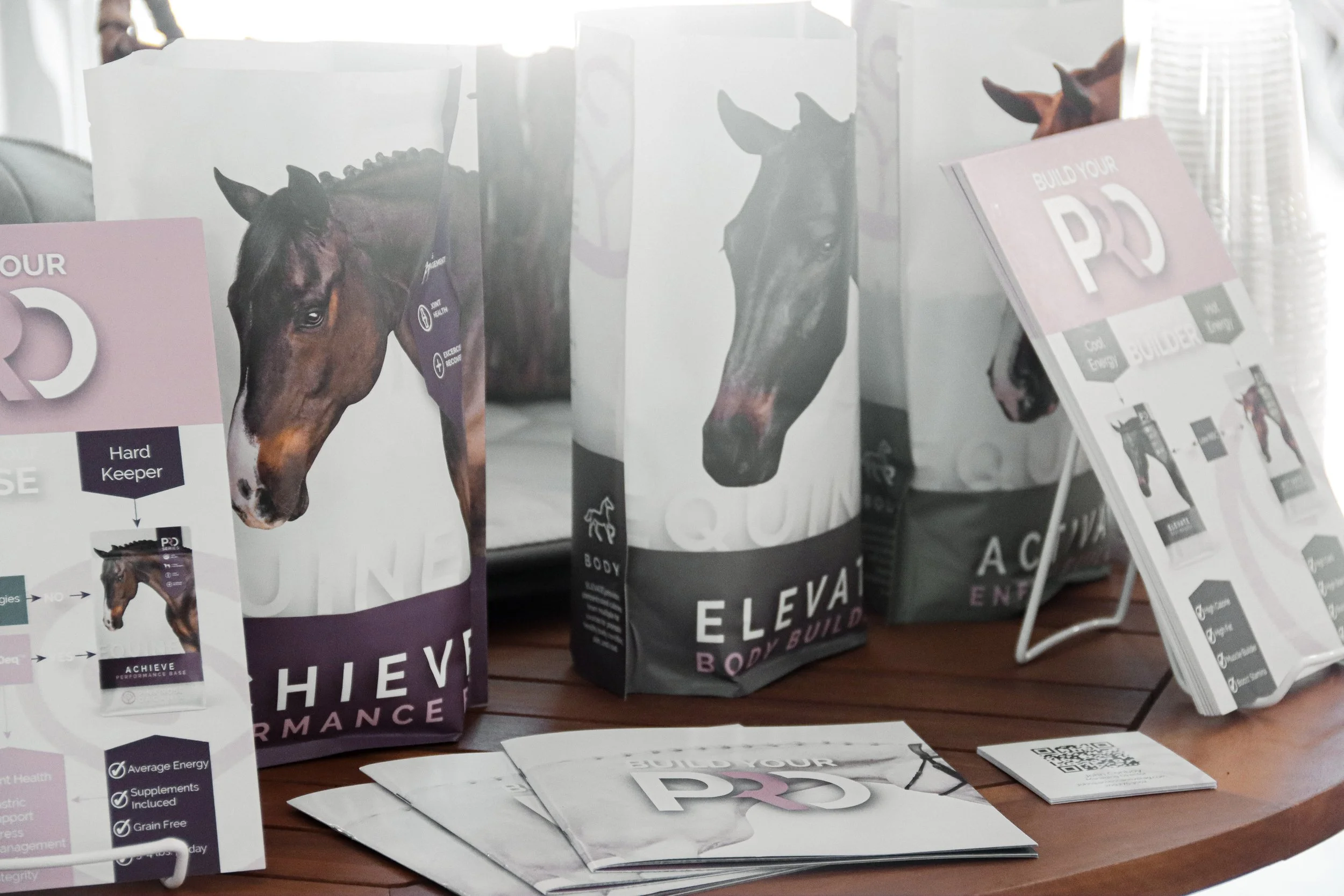Display of health and fitness products including packages featuring horse images, brochures, and promotional materials on a wooden table.