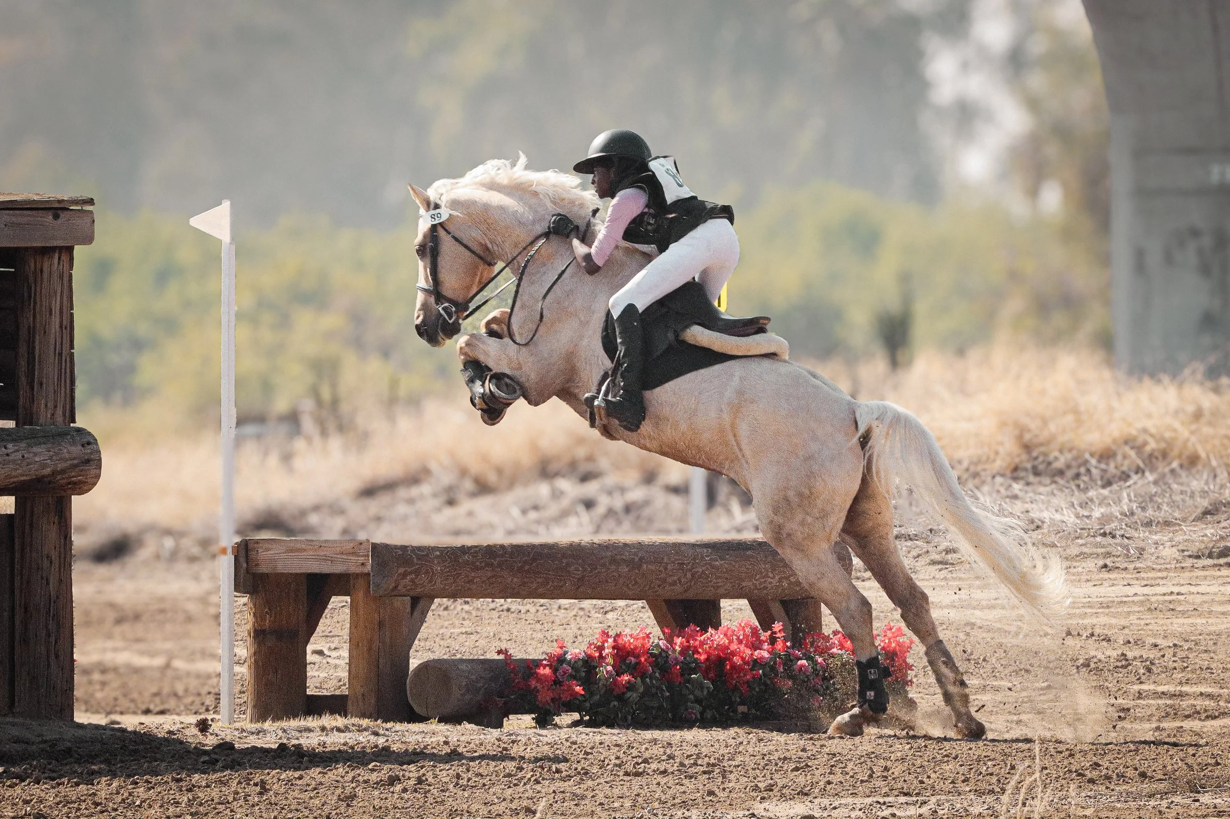 A person riding a horse over a jump during an equestrian event in an outdoor arena.