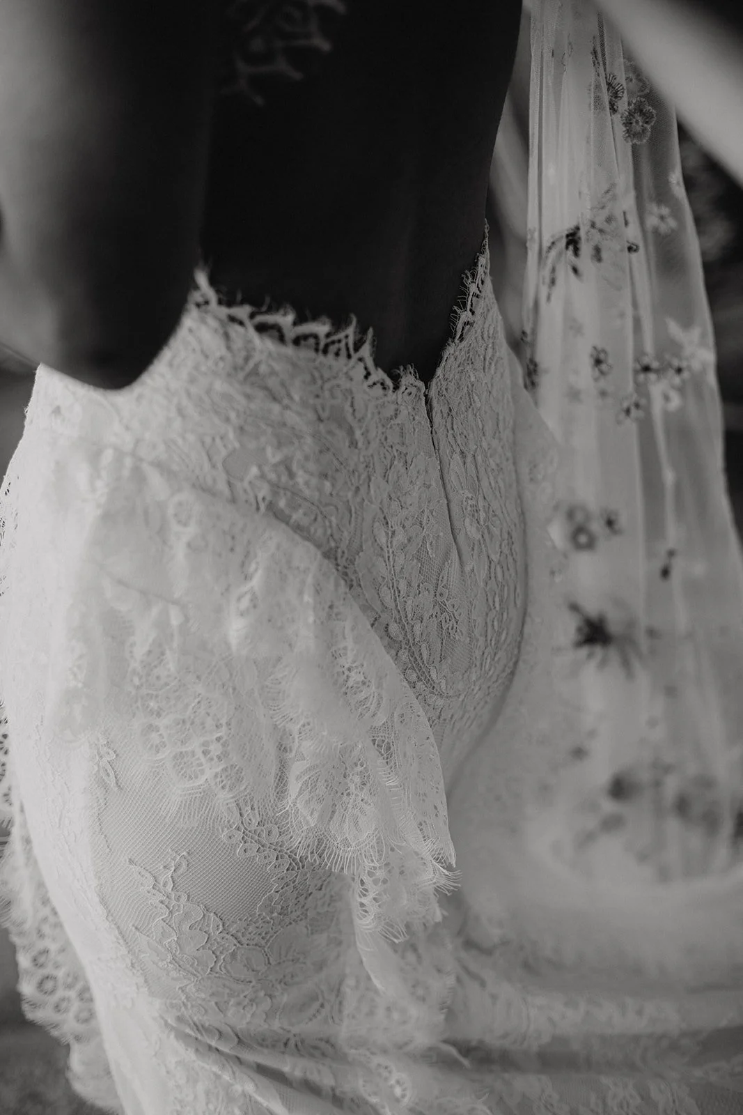 Close-up of a woman's waist in a white lace dress with ruffled edges.