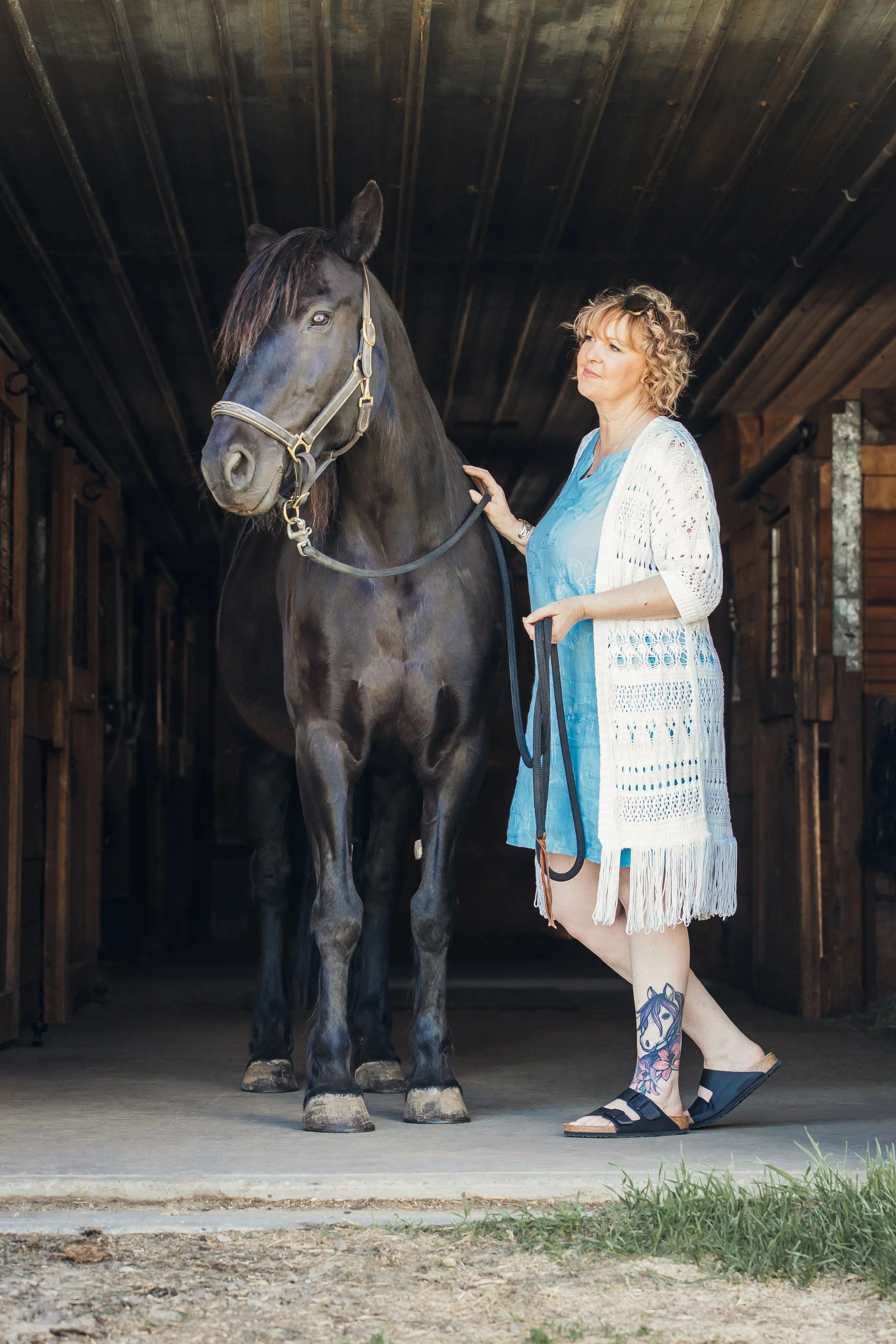 Michelle Neaves standing with Izzy, her black Canadian mare and equine partner in horse-assisted transformational work.