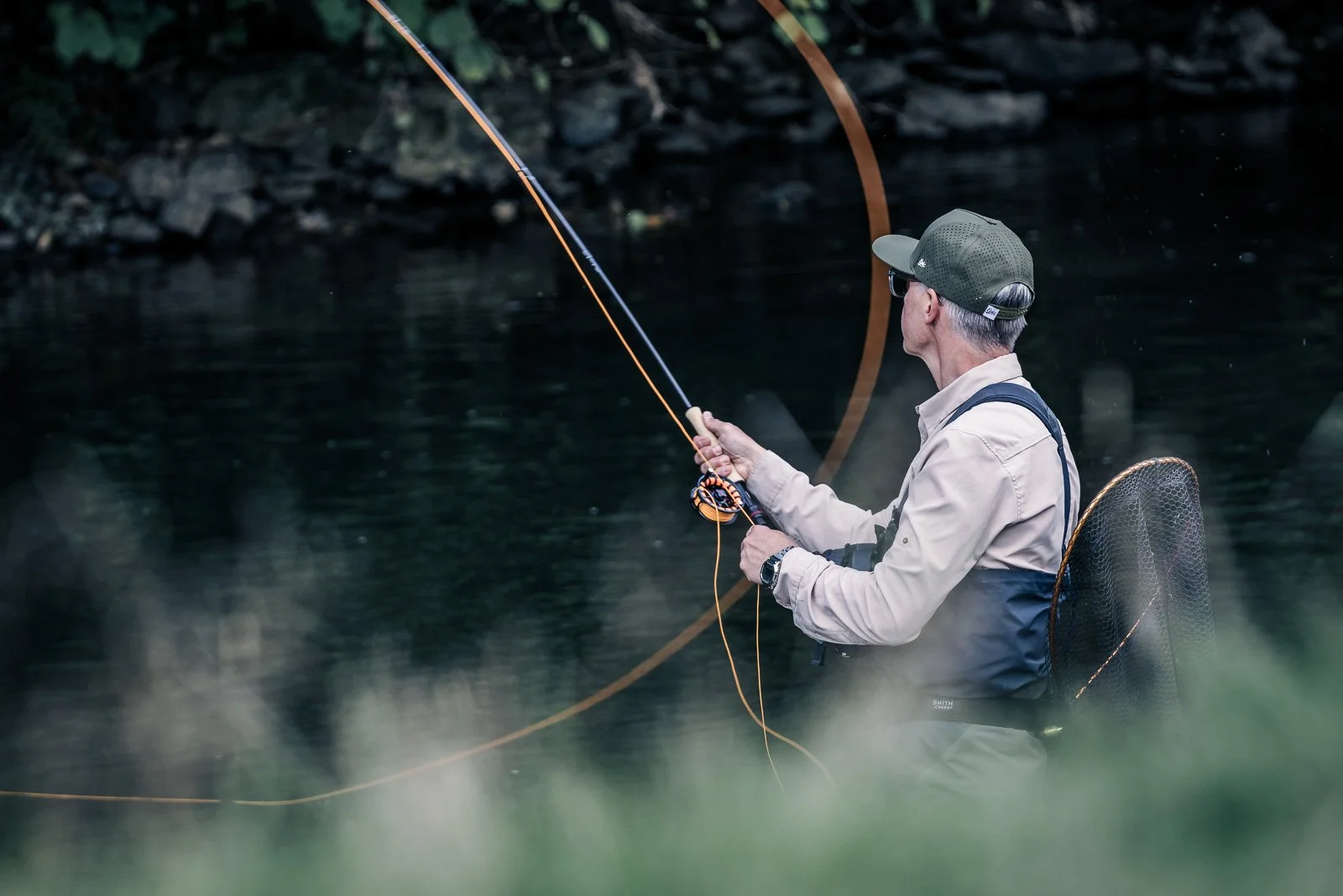 Fly fisherman casting a fishing rod in a forest stream