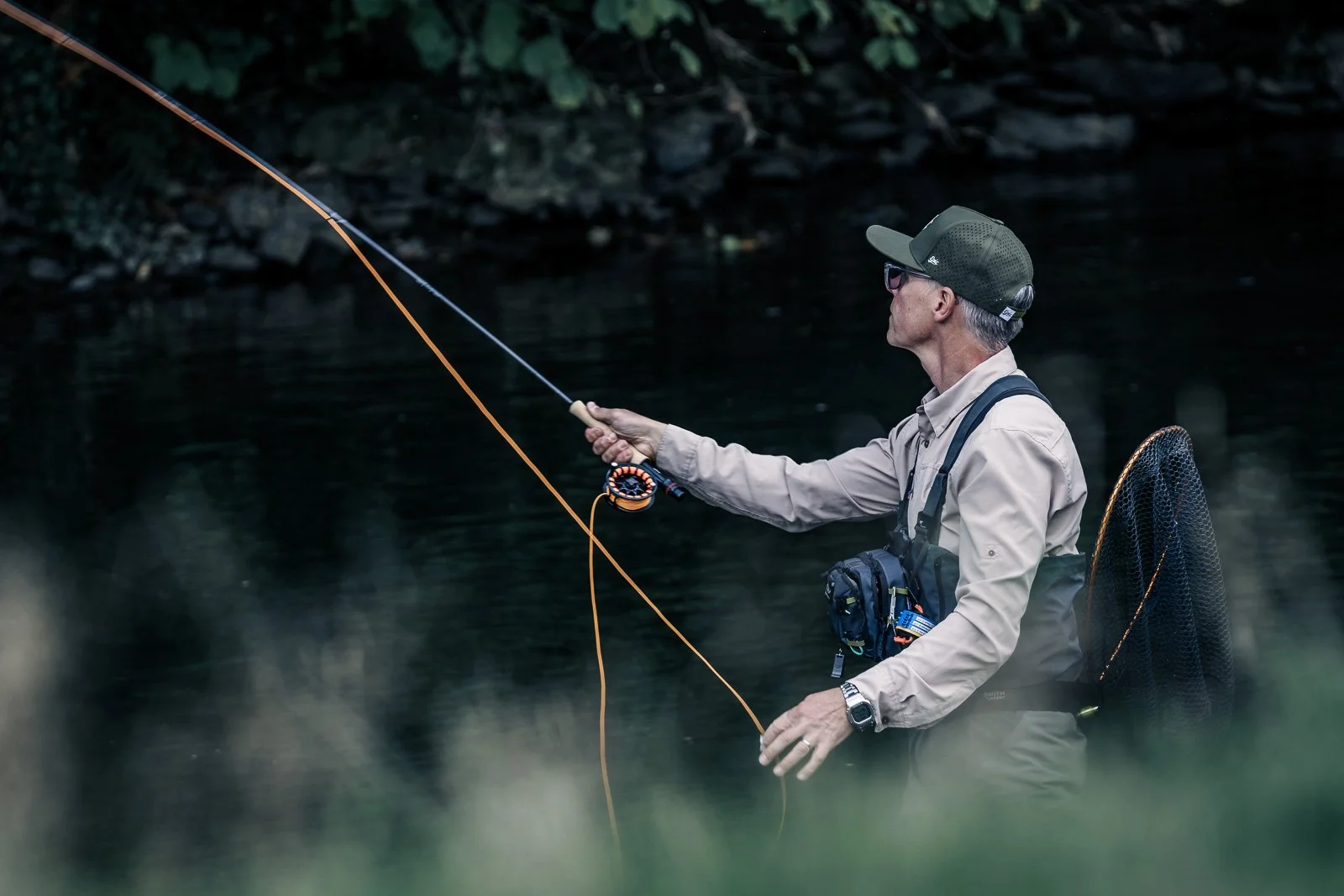 Fly fisherman casting a fly rod in a misty forest stream