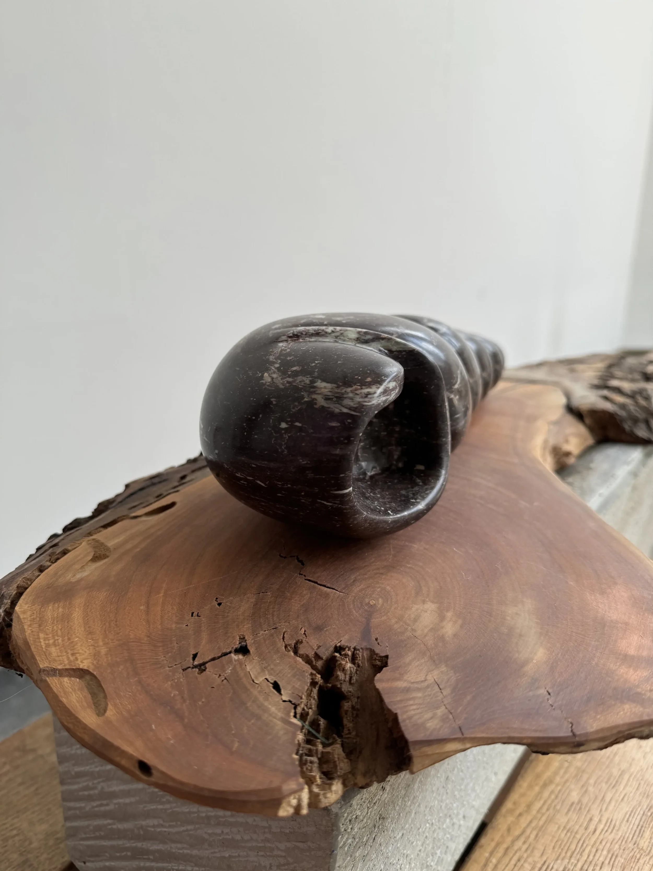 Zij aanzicht van beeld Verstilde werveling gemaakt van kobalt serpentijn liggend op een kersenhoutenplank.