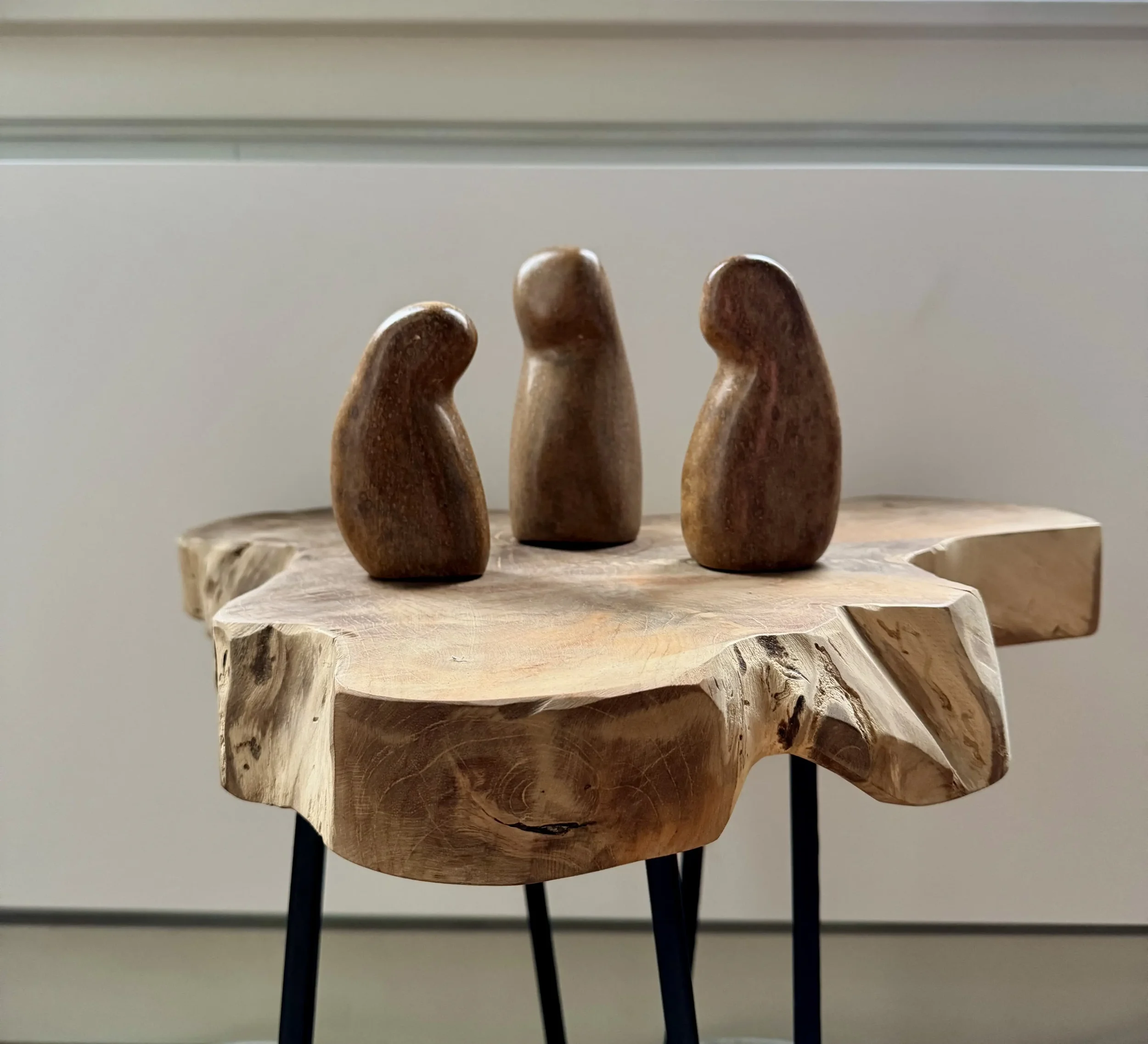 Drie bruine spekstenen figuren die bij elkaar staan op een houten tafeltje.