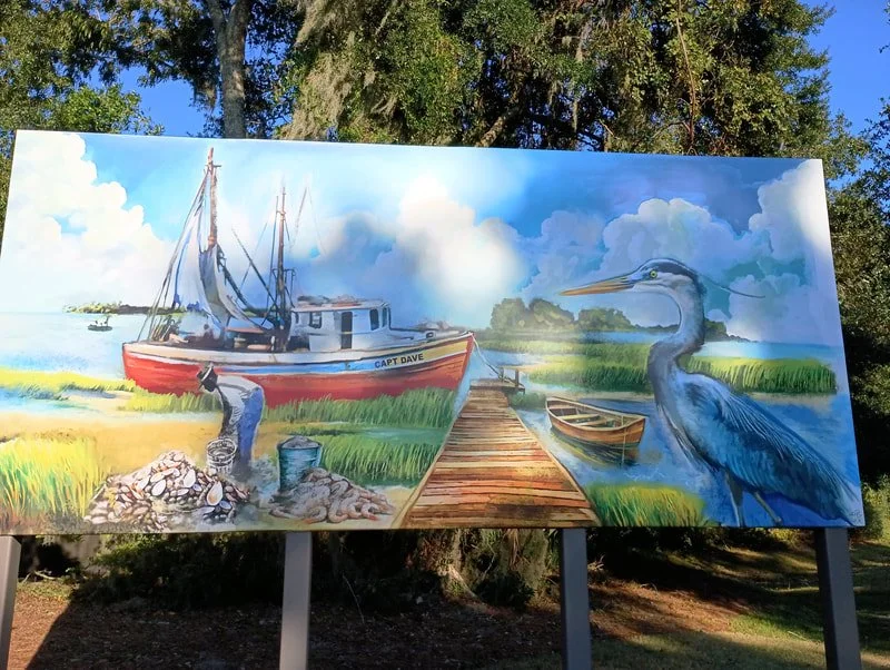 A colorful painting of a lakeside scene featuring a boat dock, a heron, and a shoreline with grass and trees under a partly cloudy sky.