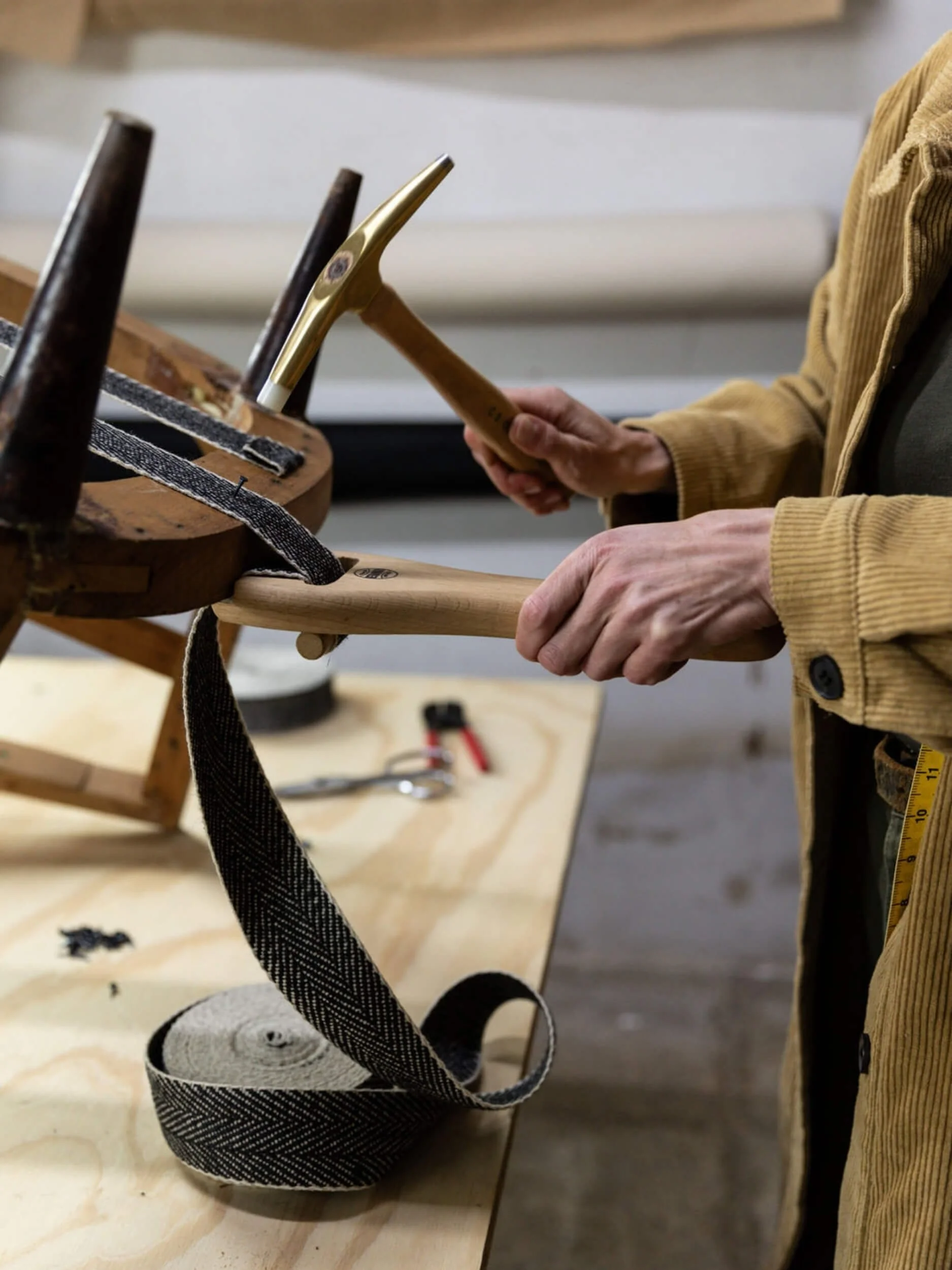 Person using chisel to carve wood on workbench in workshop.