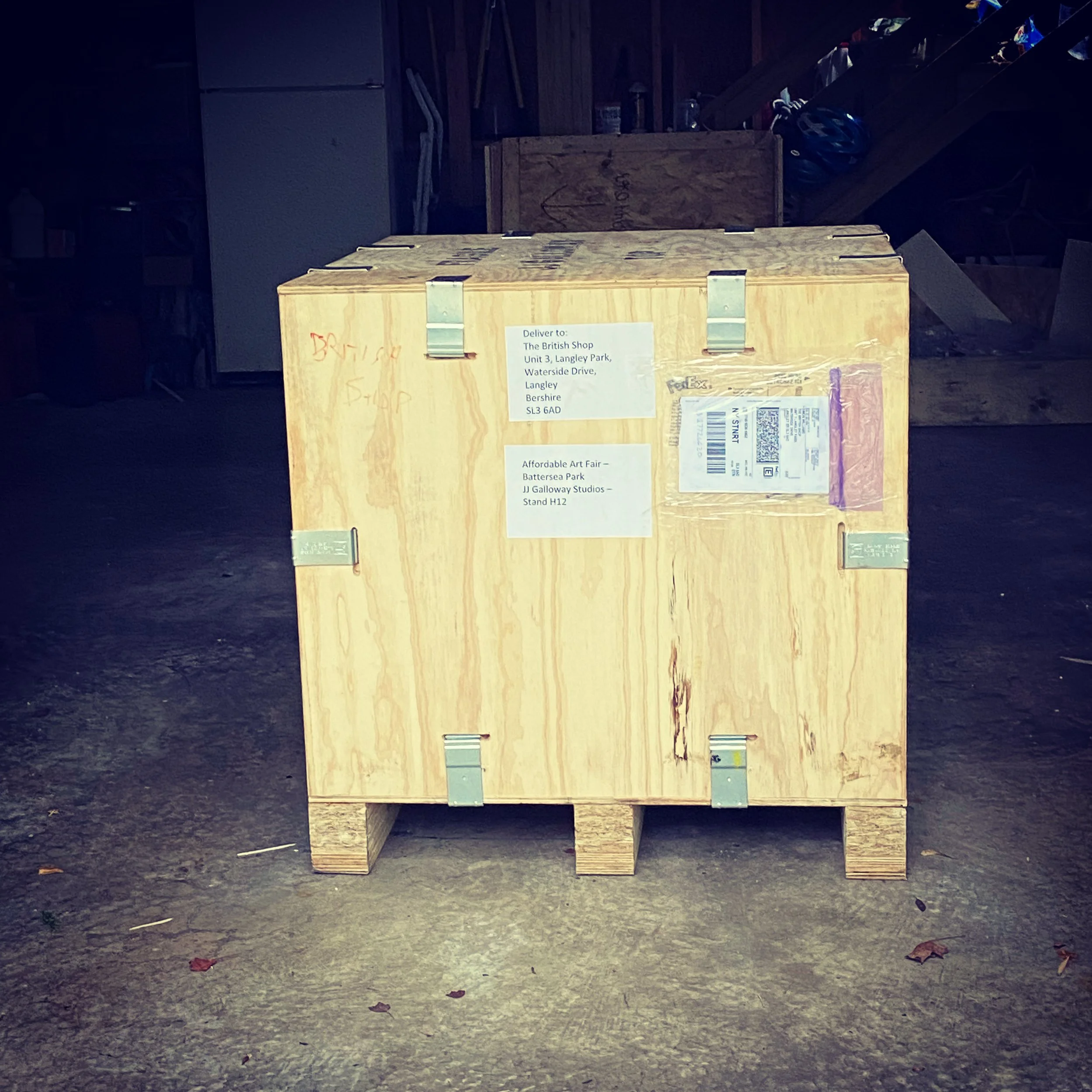 A cardboard box with shipping labels and packing tape placed on a wooden platform outdoors.