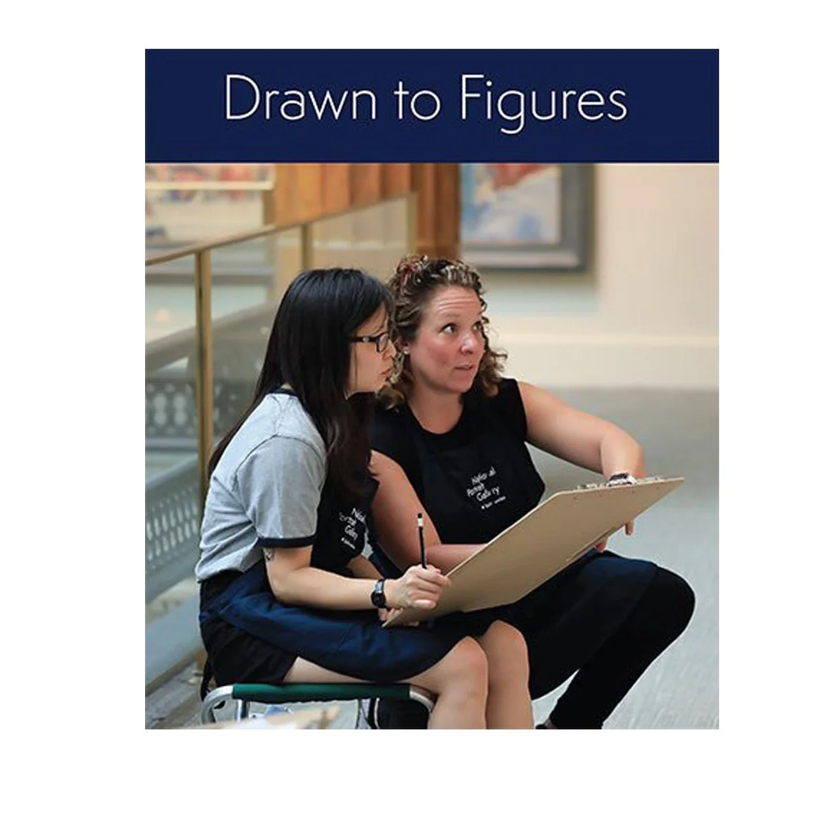 Two women, one with glasses and one with curly hair, sitting on a bench, looking at a drawing pad held by the woman with curly hair, in an indoor setting with artwork on the wall and a railing behind them.