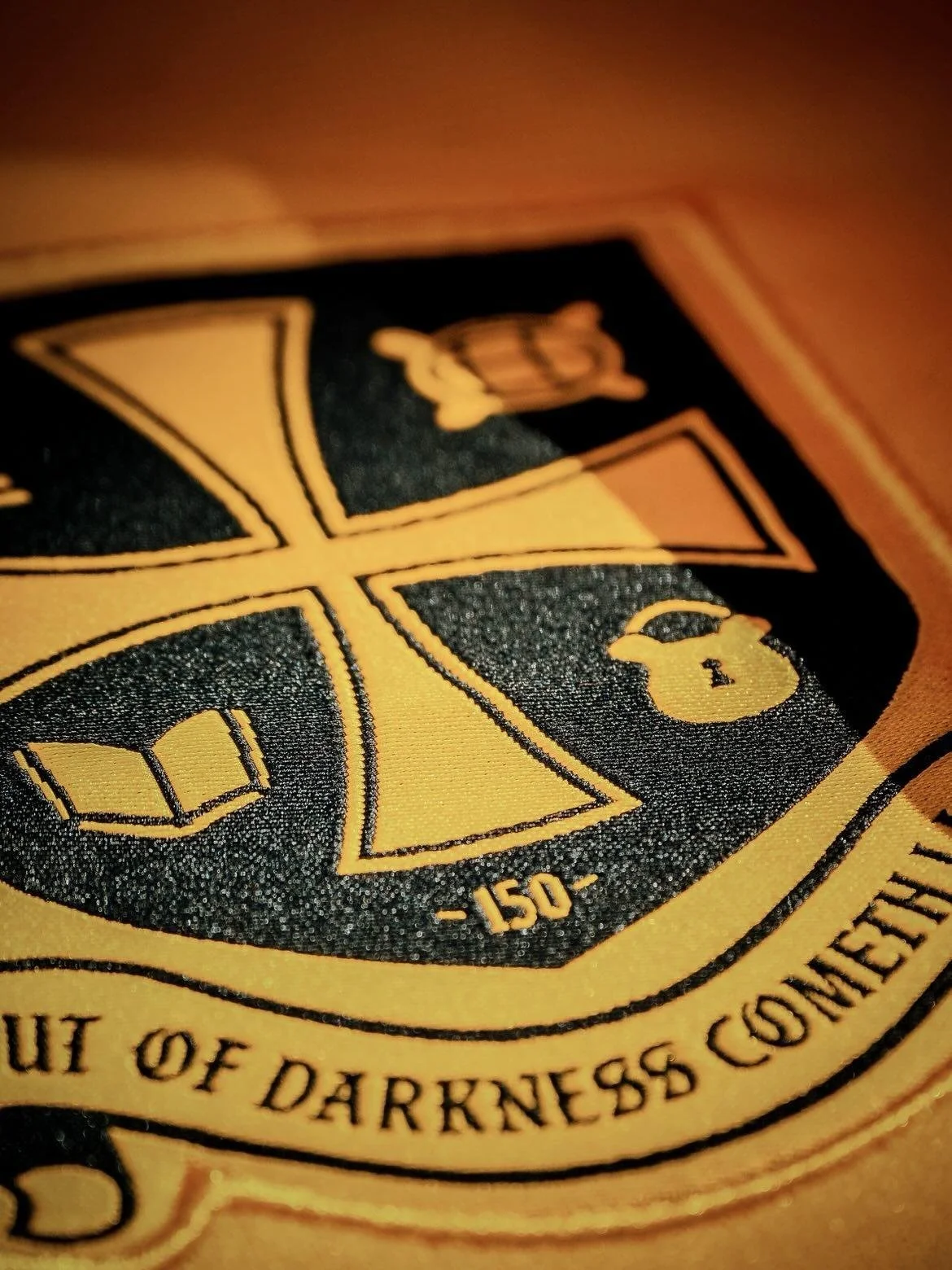 Close-up of a sticker or patch with a golden shield design featuring a book, a key, and a crown with a lock, with text indicating a confidence level of 150.