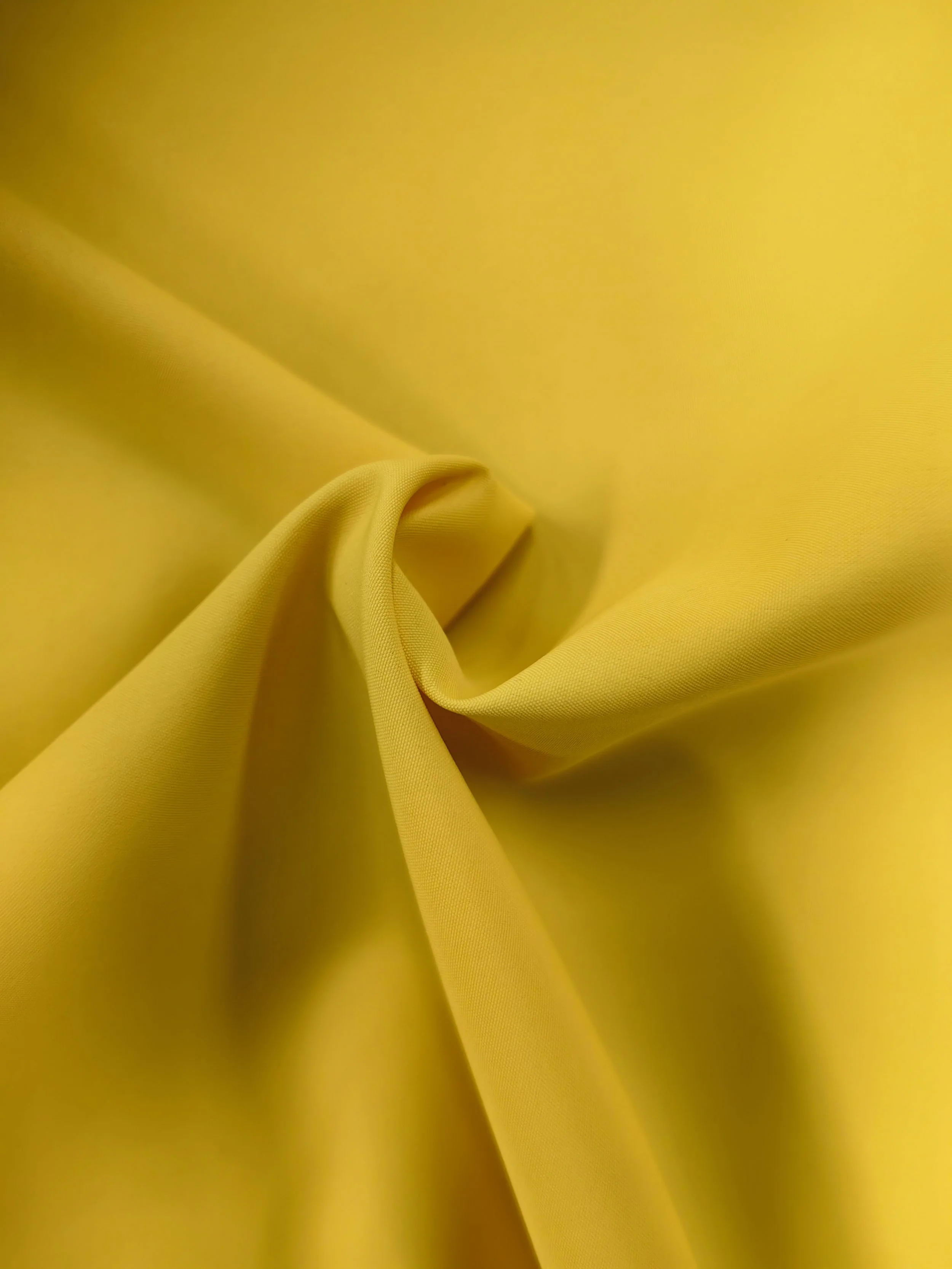 Close-up of yellow fabric with some folds and wrinkles.