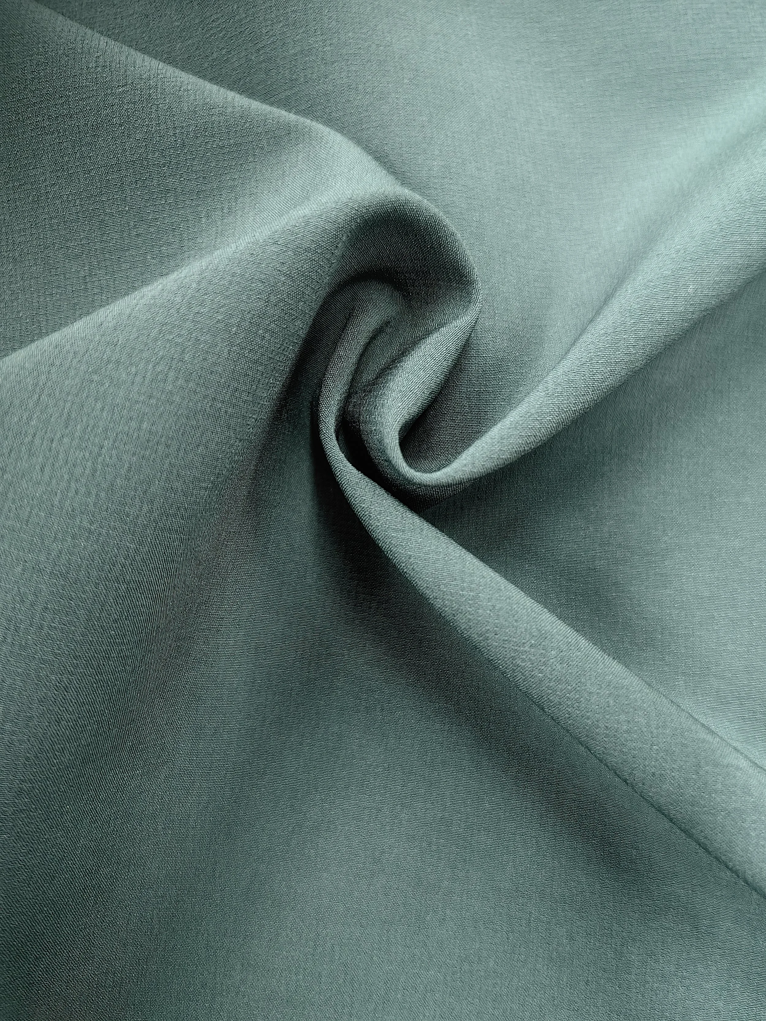 Close-up of smooth, teal-colored fabric with gentle folds and a slightly textured surface.