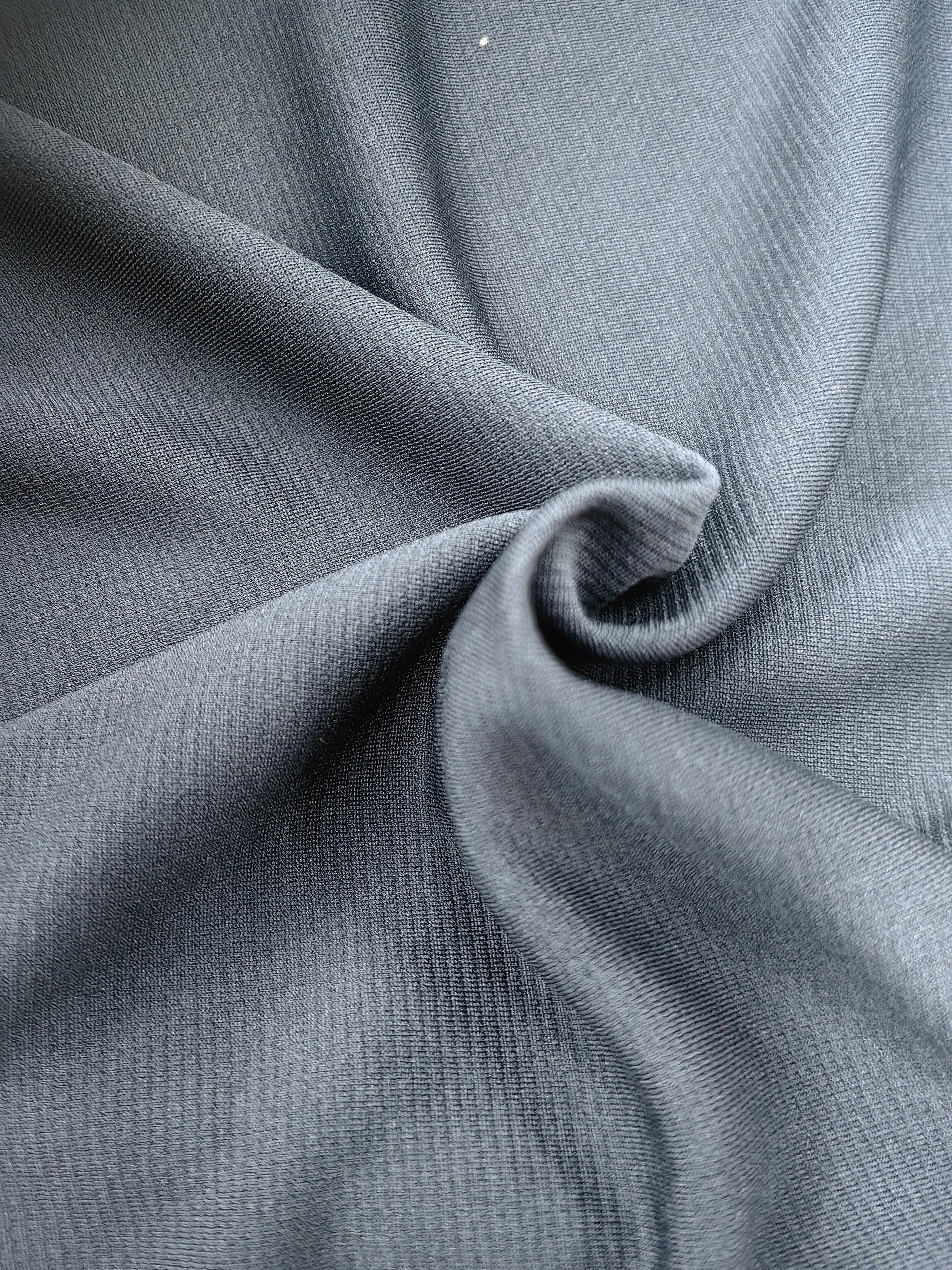 A close-up view of grey fabric with a textured weave pattern, showing slight folds and creases.