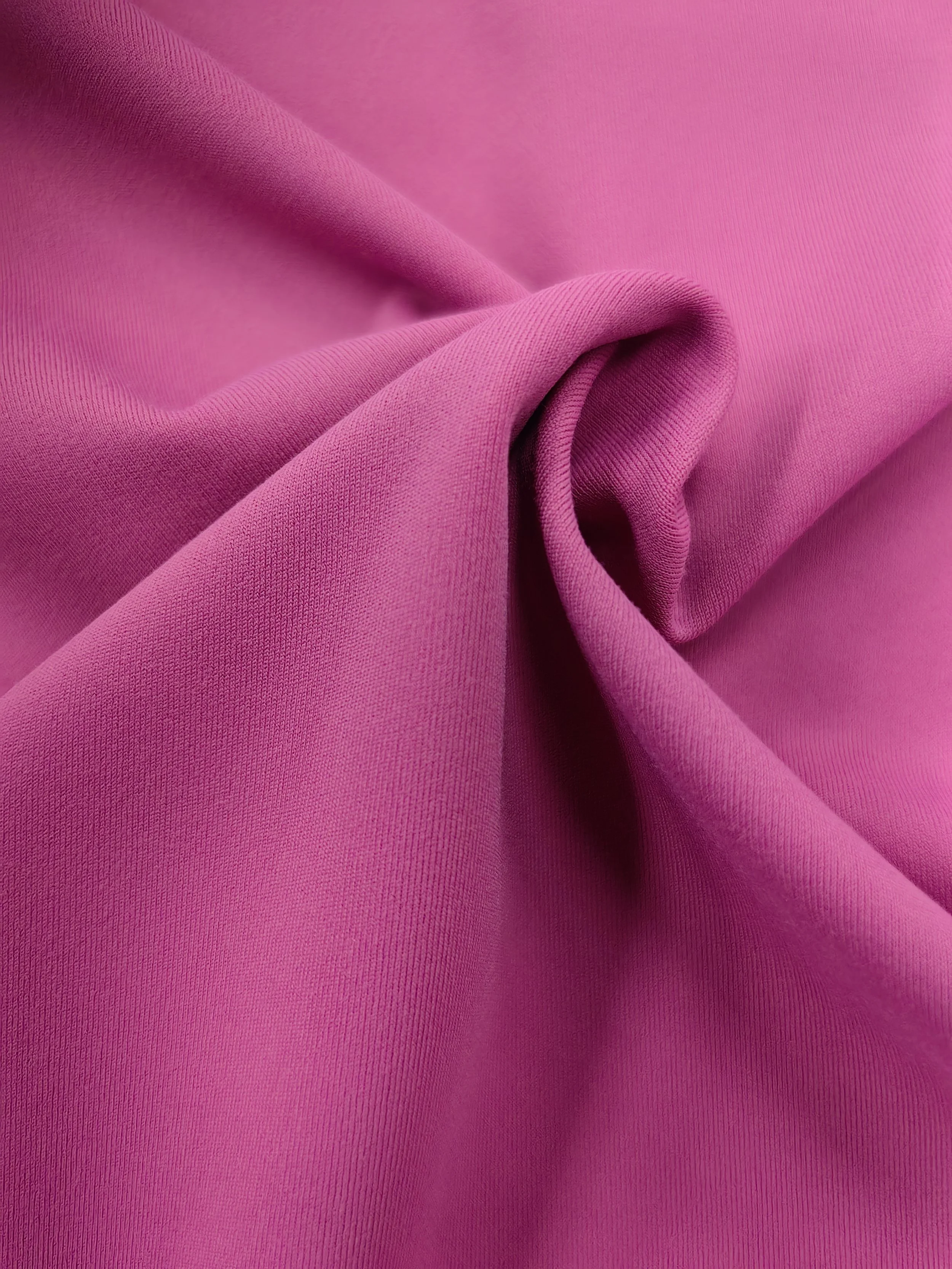 Close-up of a pink fabric with a textured surface, draped and folded.