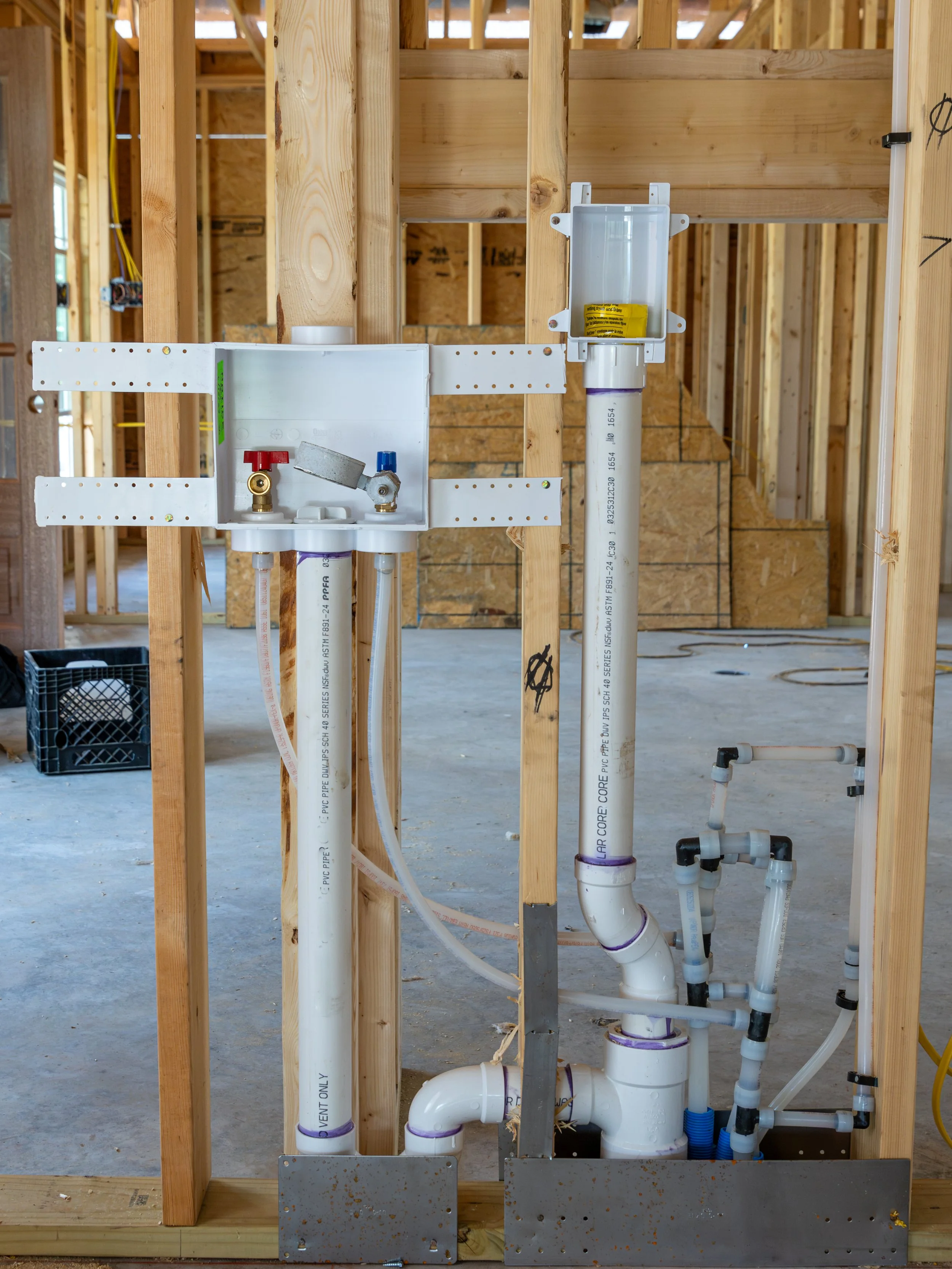Water supply pipes and plumbing fixtures installed in building framing under construction.