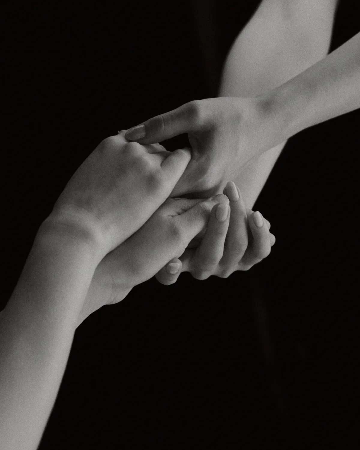 Monochrome close-up of hands performing massage or therapeutic touch on arm