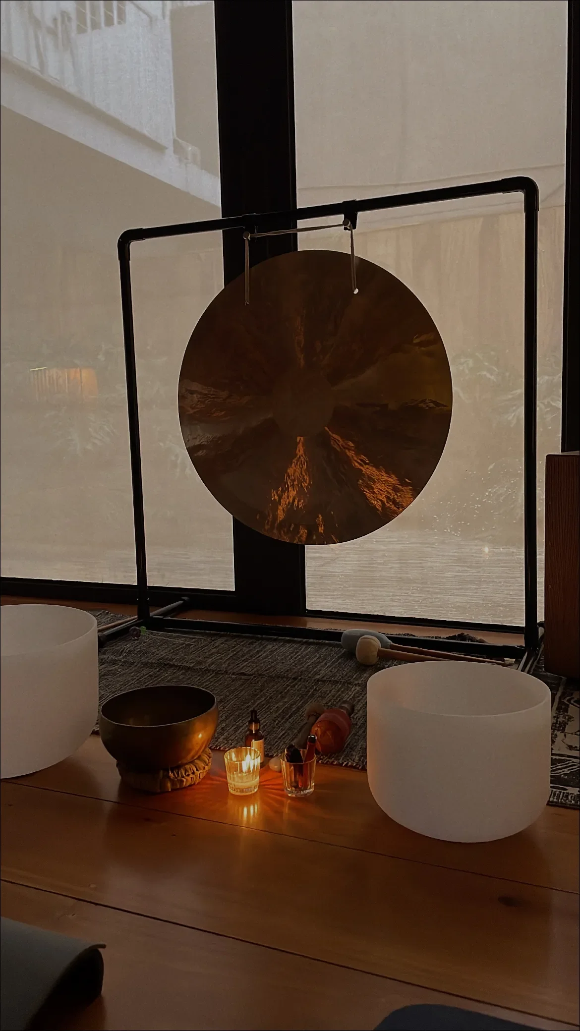 Ornate singing bowl with wooden mallet and dried botanicals in warm candlelit ambiance