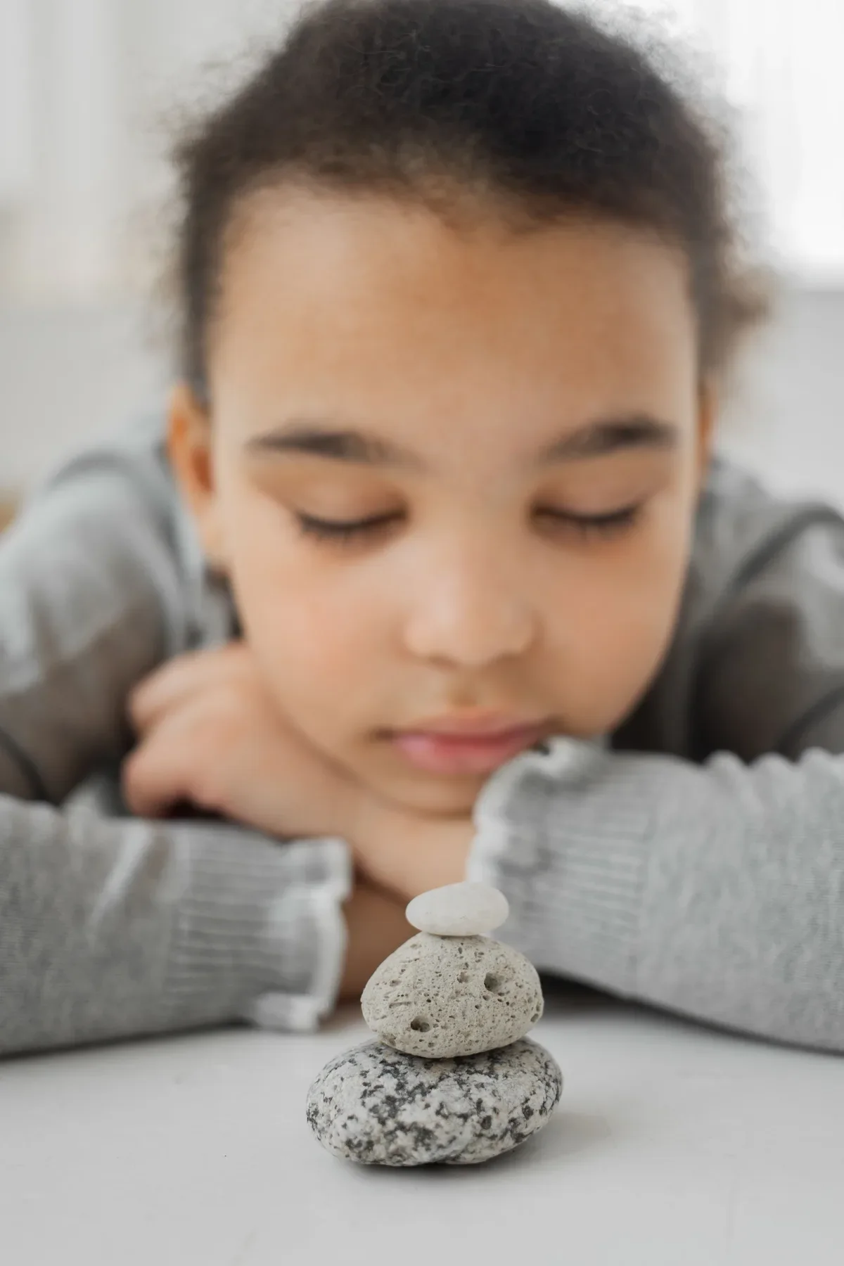 Child gazing at stacked stones in mindful meditation practice