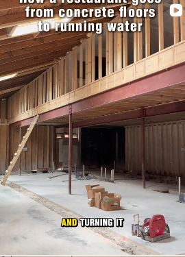 Construction site of a building with wooden framing and concrete floors, with construction tools and equipment on the ground.