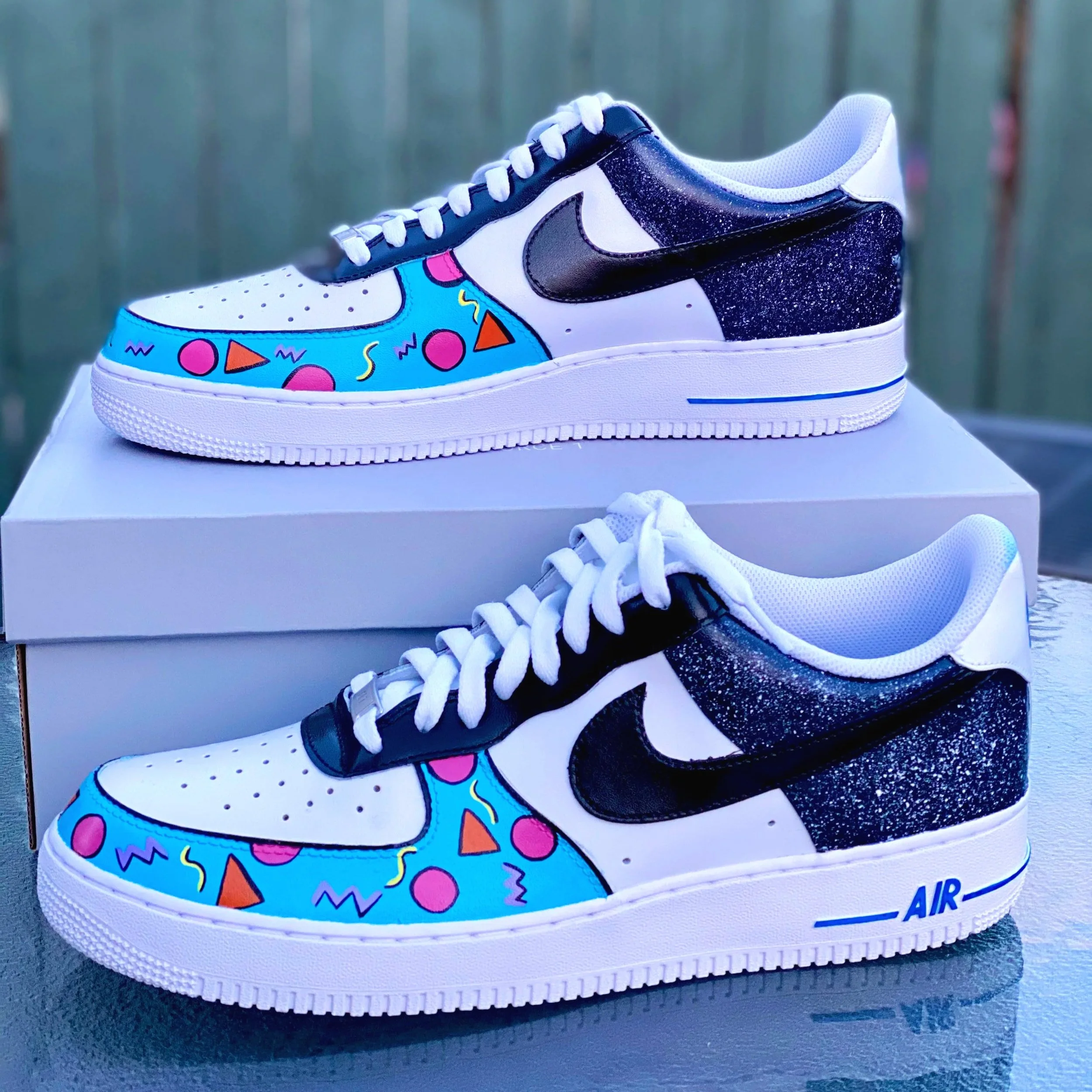 Nike Air sneaker with a colorful, geometric, and abstract pattern on the toe area, set on a white shoebox.