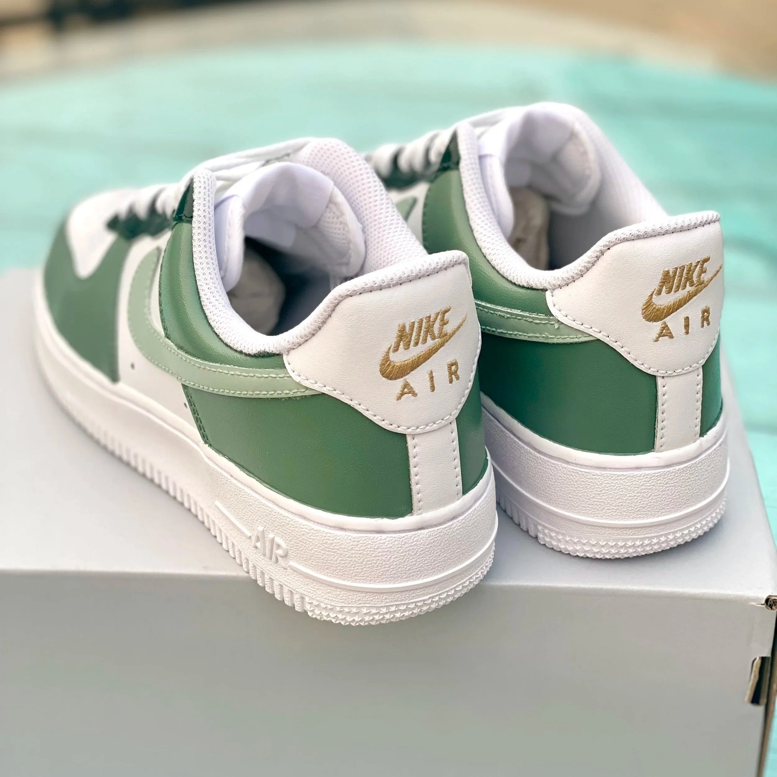 Close-up of a pair of Nike Air sneakers with green and white color, placed on a white surface.
