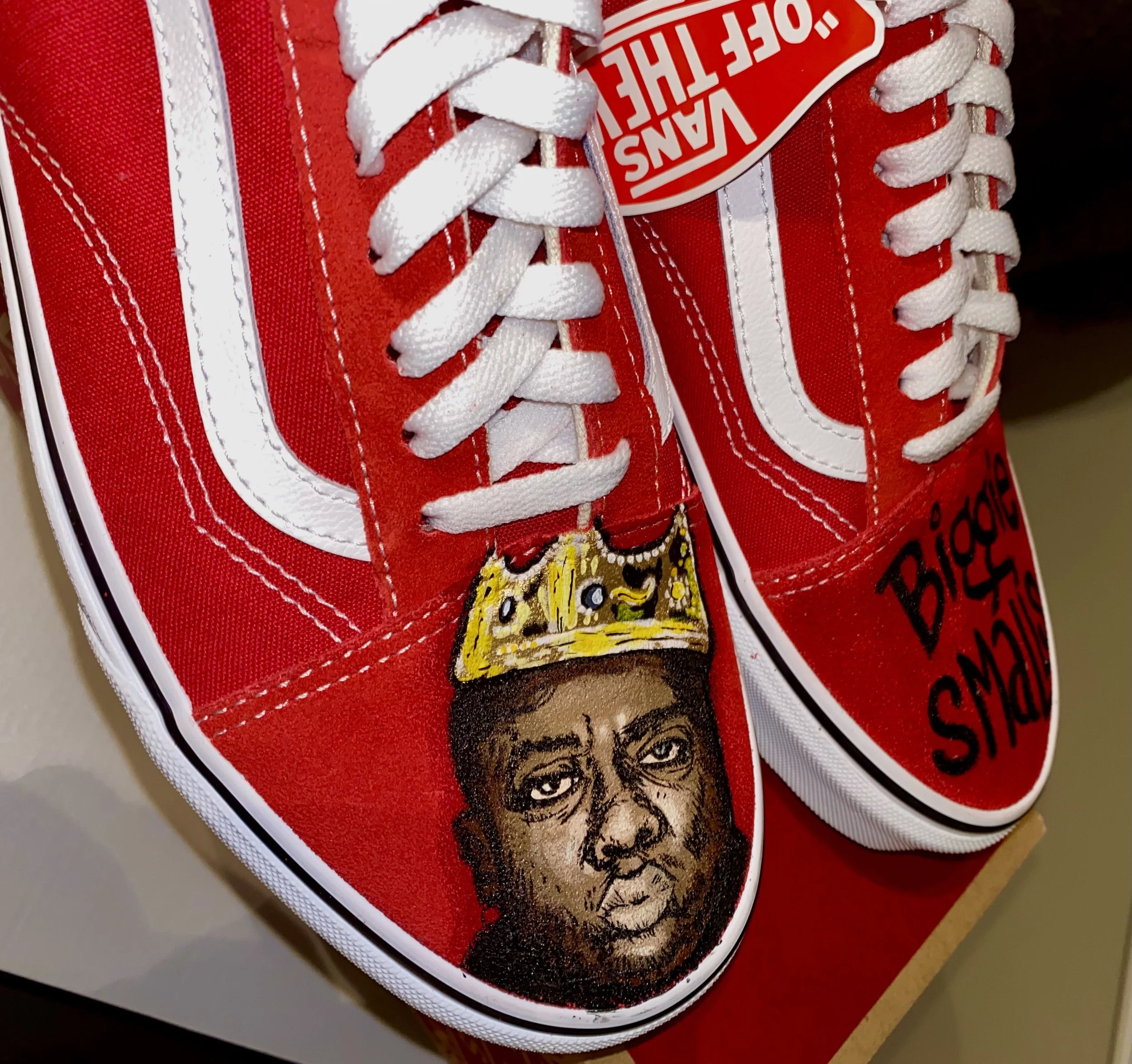 Close-up of a red Vans sneaker showing the white laces, Vans logo on the tongue, and a part of a graphic featuring a tiger and a face.