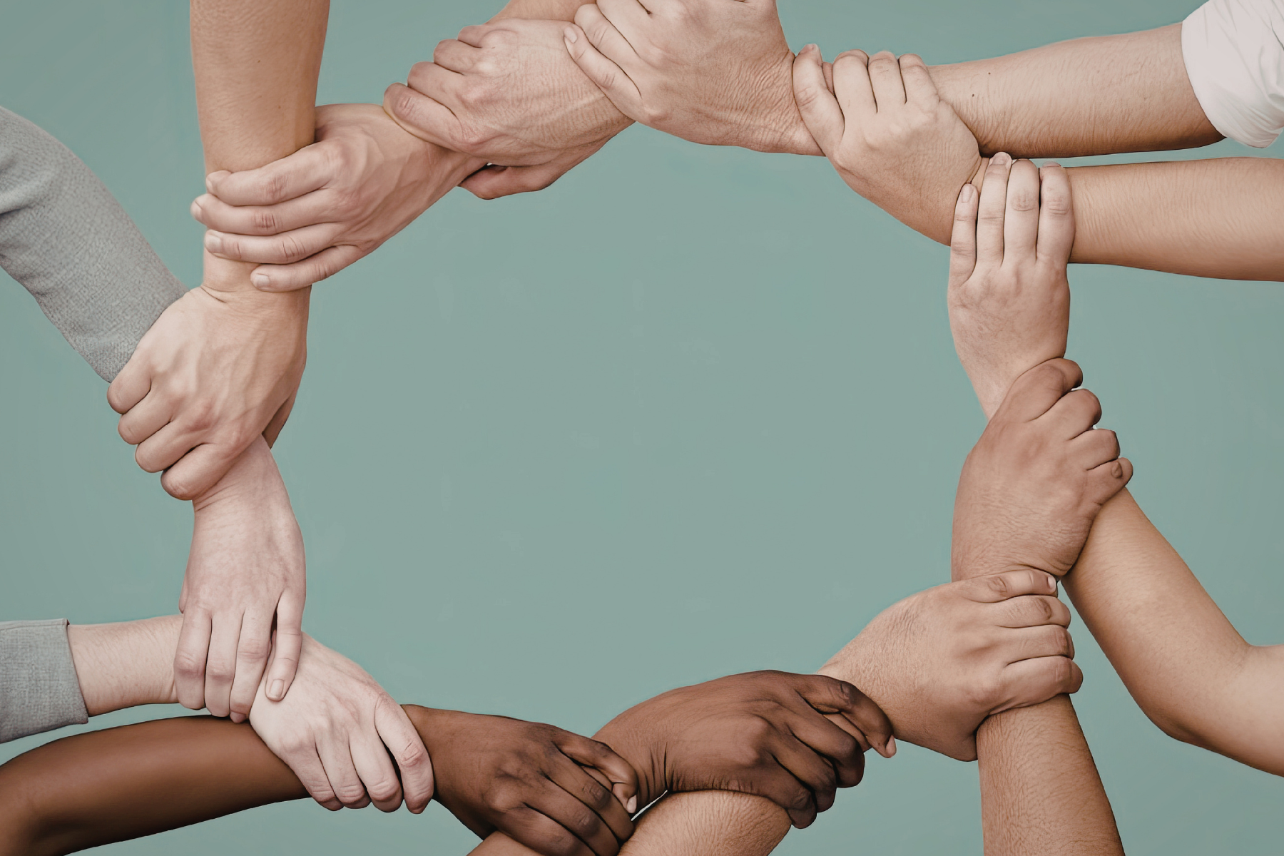 Hands of diverse skin tones clasped together in a circle.