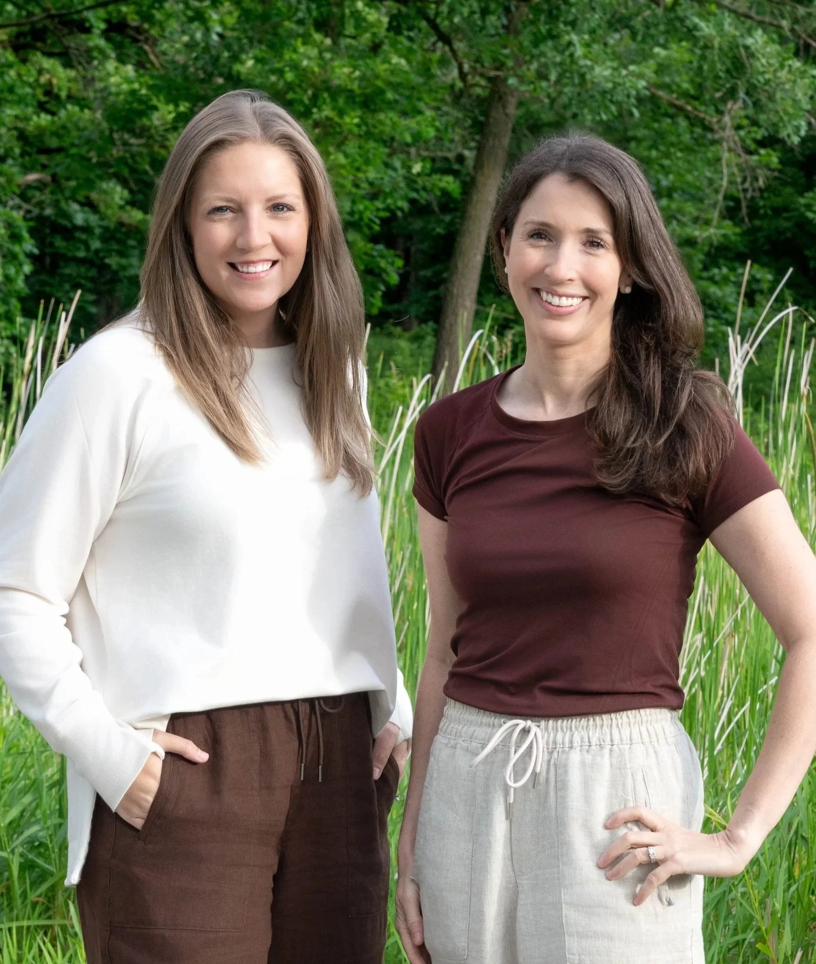 Rooted Fertility Co. founders Laura and Ashlee standing together outdoors, smiling.