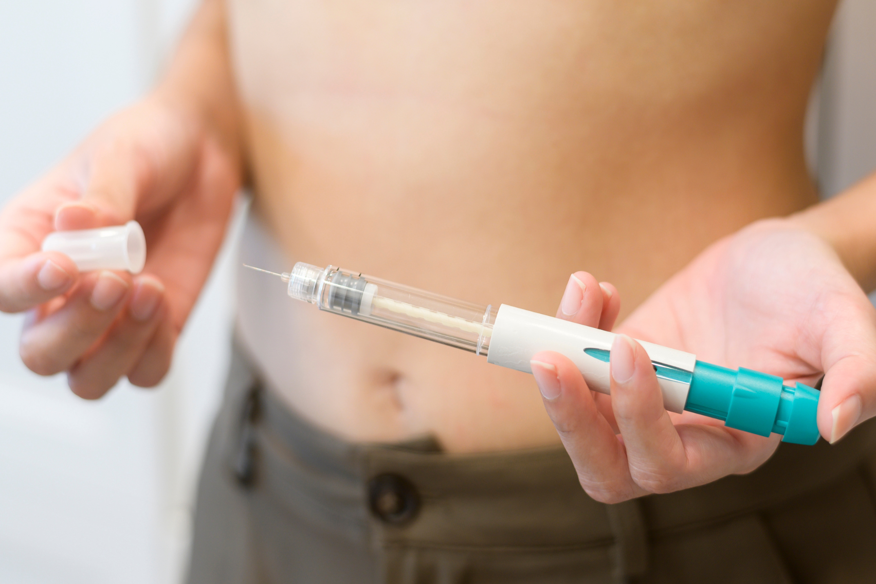 A person holding an injection pen to the abdomen, preparing a fertility medication shot.