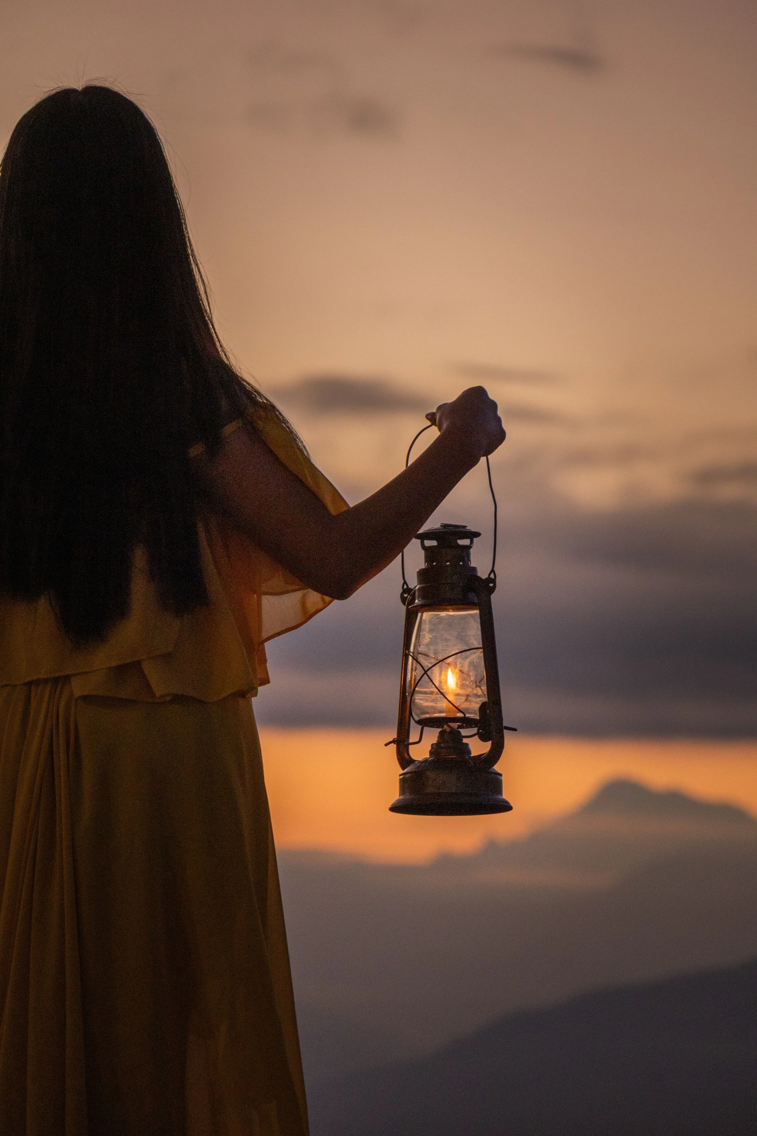 Woman holding a lantern at sunset representing nurse-led guidance and support for the fertility journey