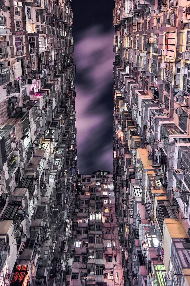 Looking up from the courtyard of the Monster Building in Quarry Bay Hong Kong 2021, dense apartment facades and a narrow violet sky