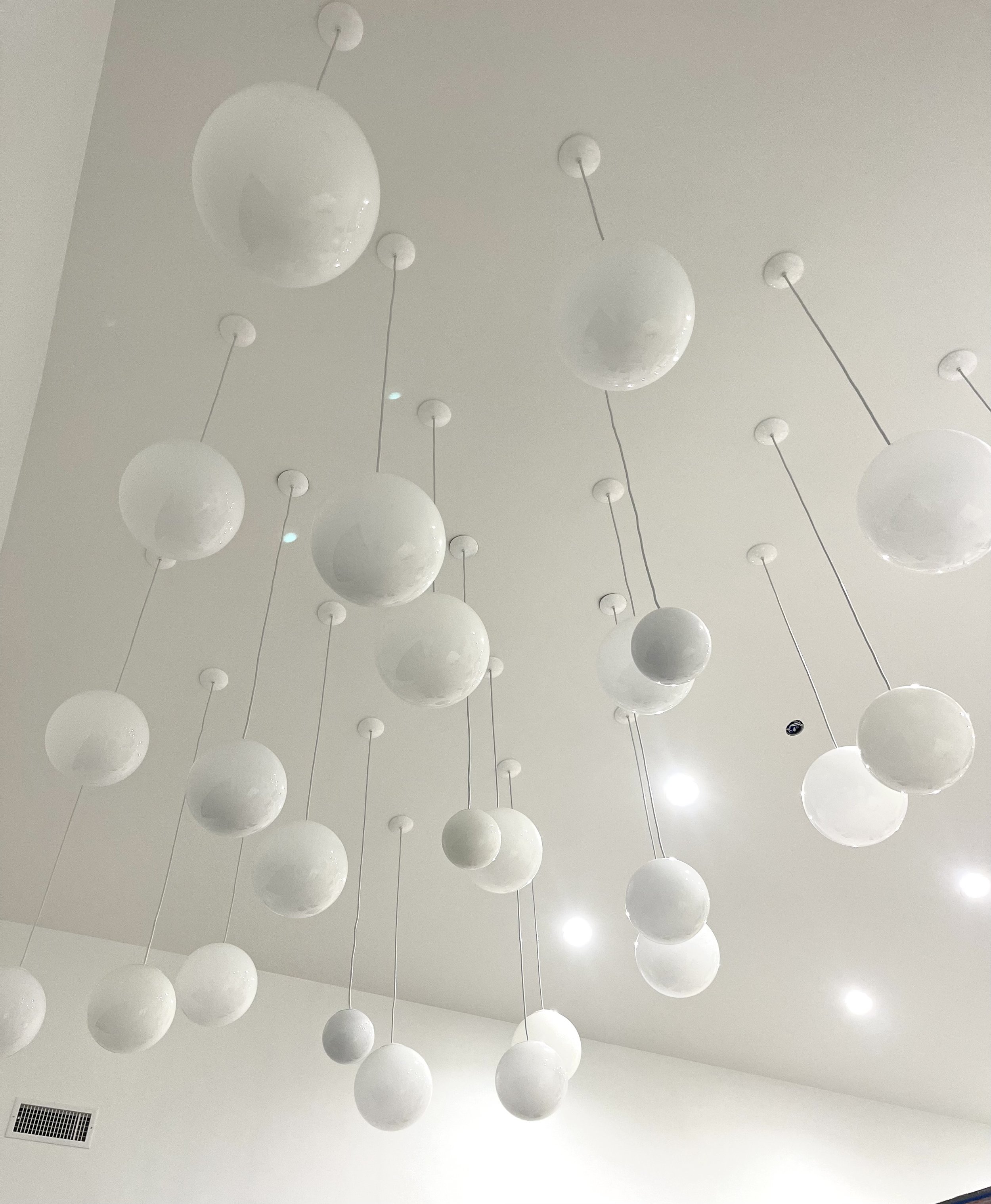 Ceiling with multiple white spherical pendant lights hanging at different heights.