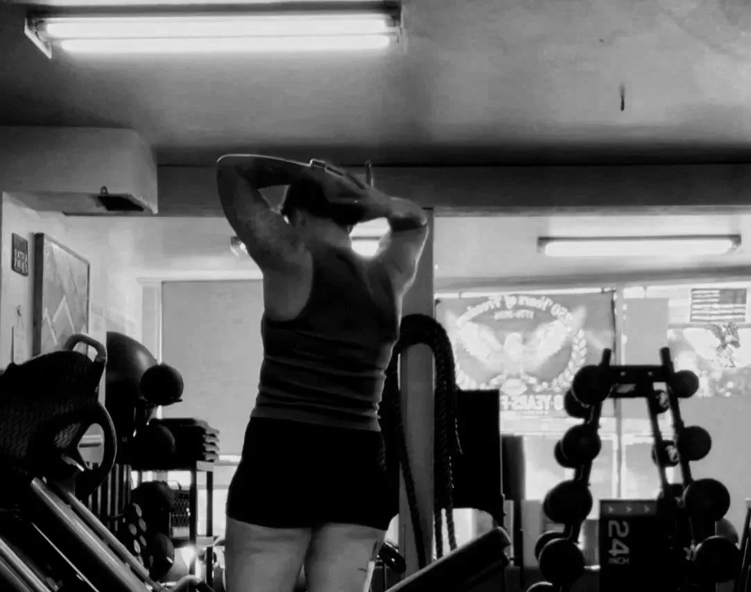 A person in a Mariposa, CA gym, surrounded by gym equipment and weights.
