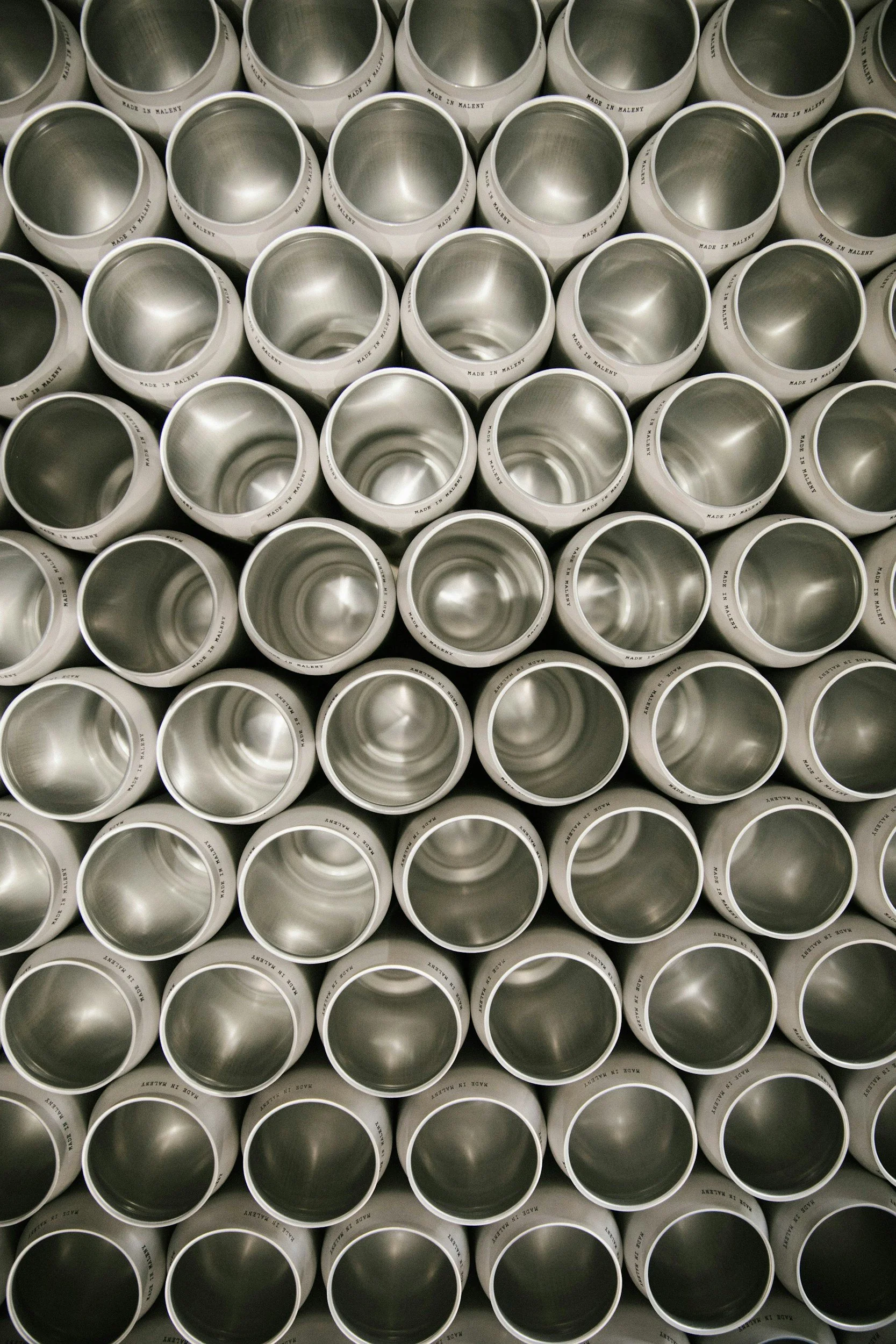 A stack of white metal cans with open tops, arranged in rows.