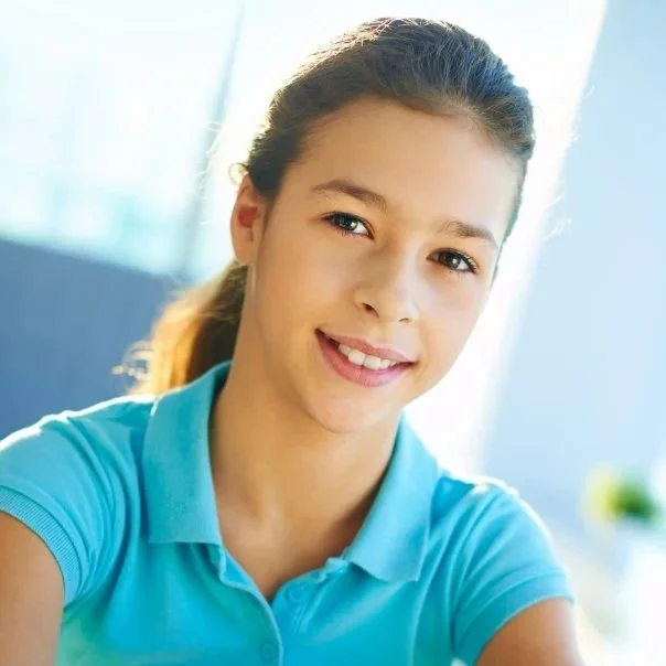 Joven mujer con camiseta azul sonriendo, en un ambiente bien iluminado.