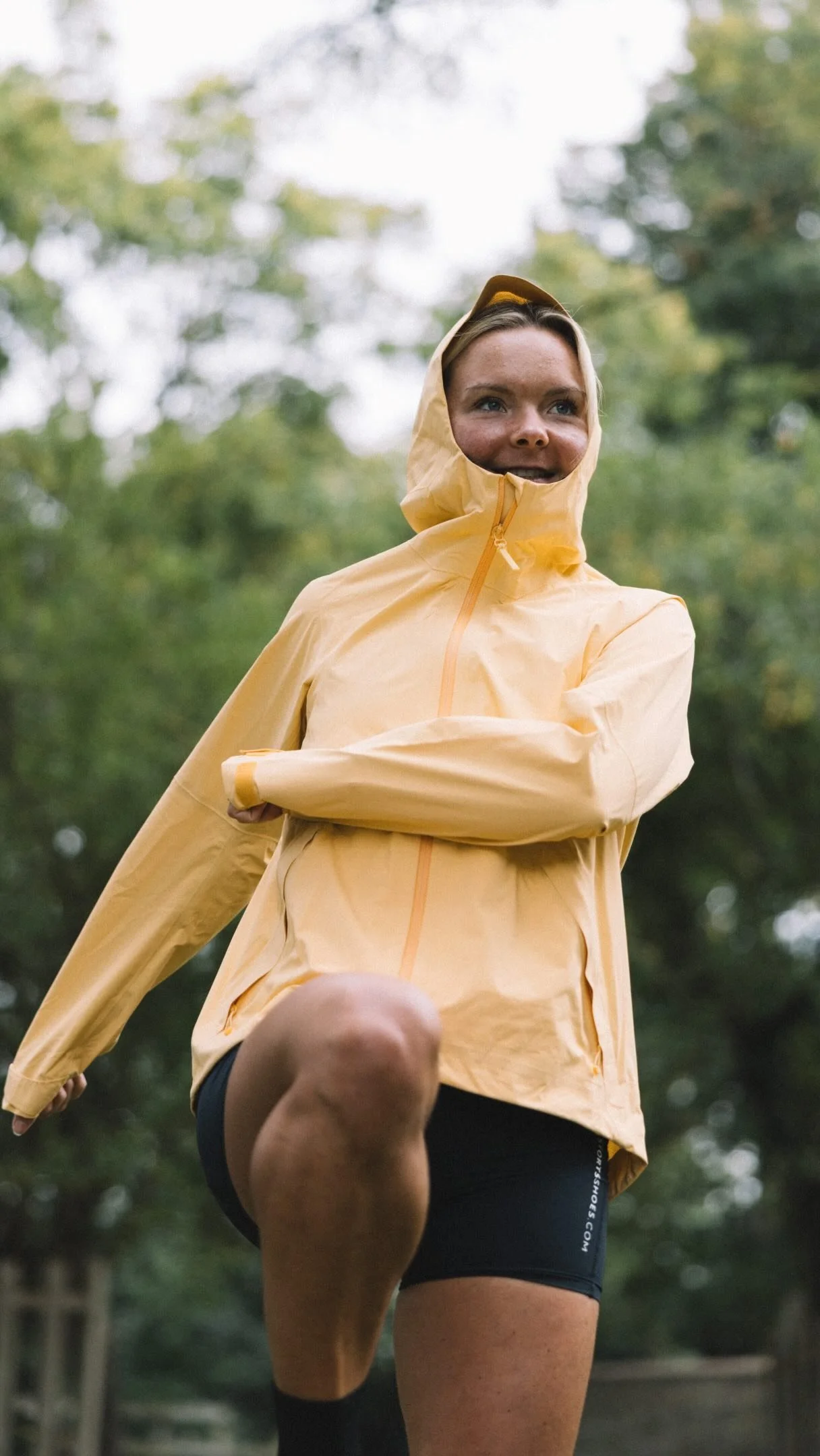 Imo in a yellow raincoat stretching with one knee up