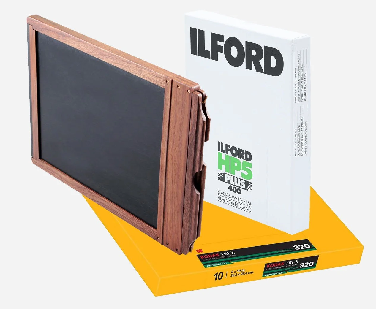A wood film holder and a box of 8x10 large format black-and-white sheet film by Kodak and Ilford.