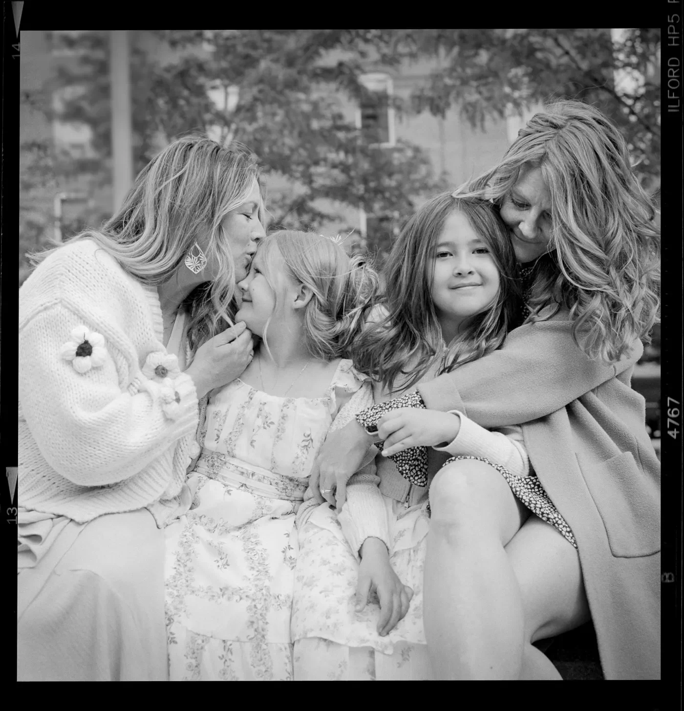 A portrait of two moms and their daughters embracing.
