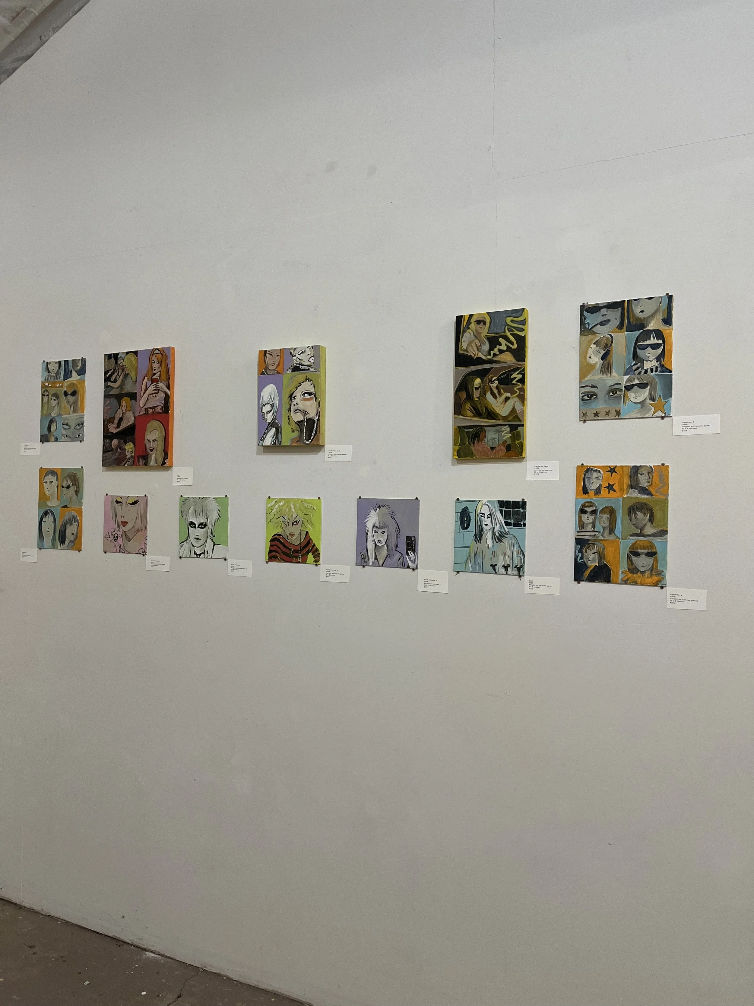 Gallery wall with multiple colorful pop art portraits of women, each with labels beneath, on a white exhibition wall.