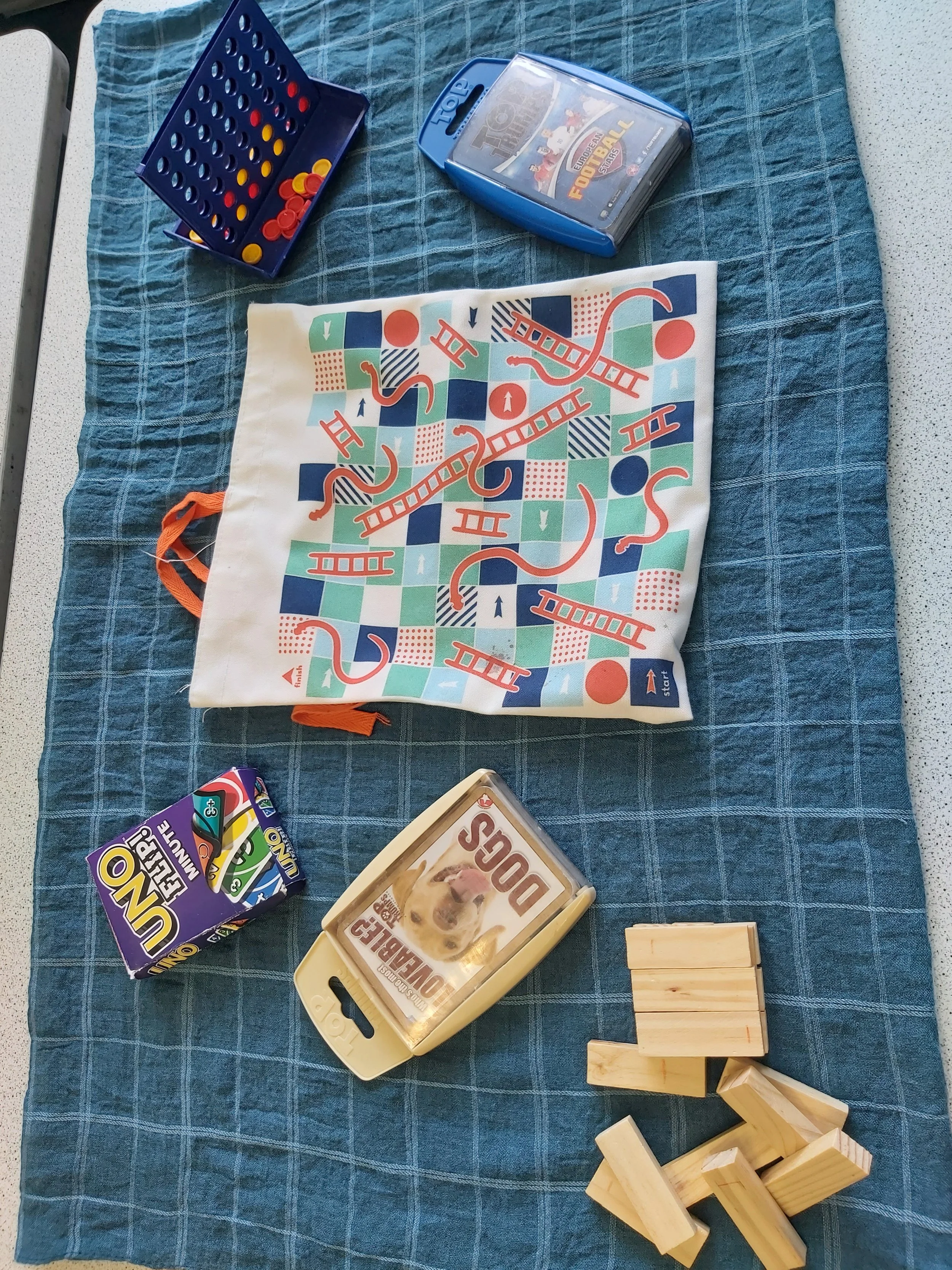 Board game setup on a blue cloth with game pieces, a game box, and wooden blocks.