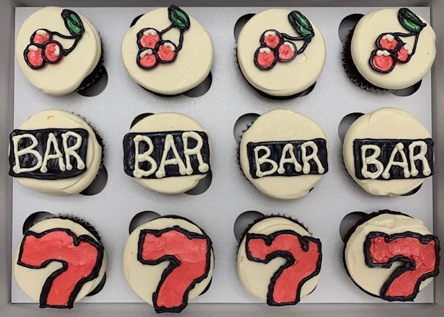 Decorated cookies with cherry designs, 'BAR' text, and red number '7's on a white surface.