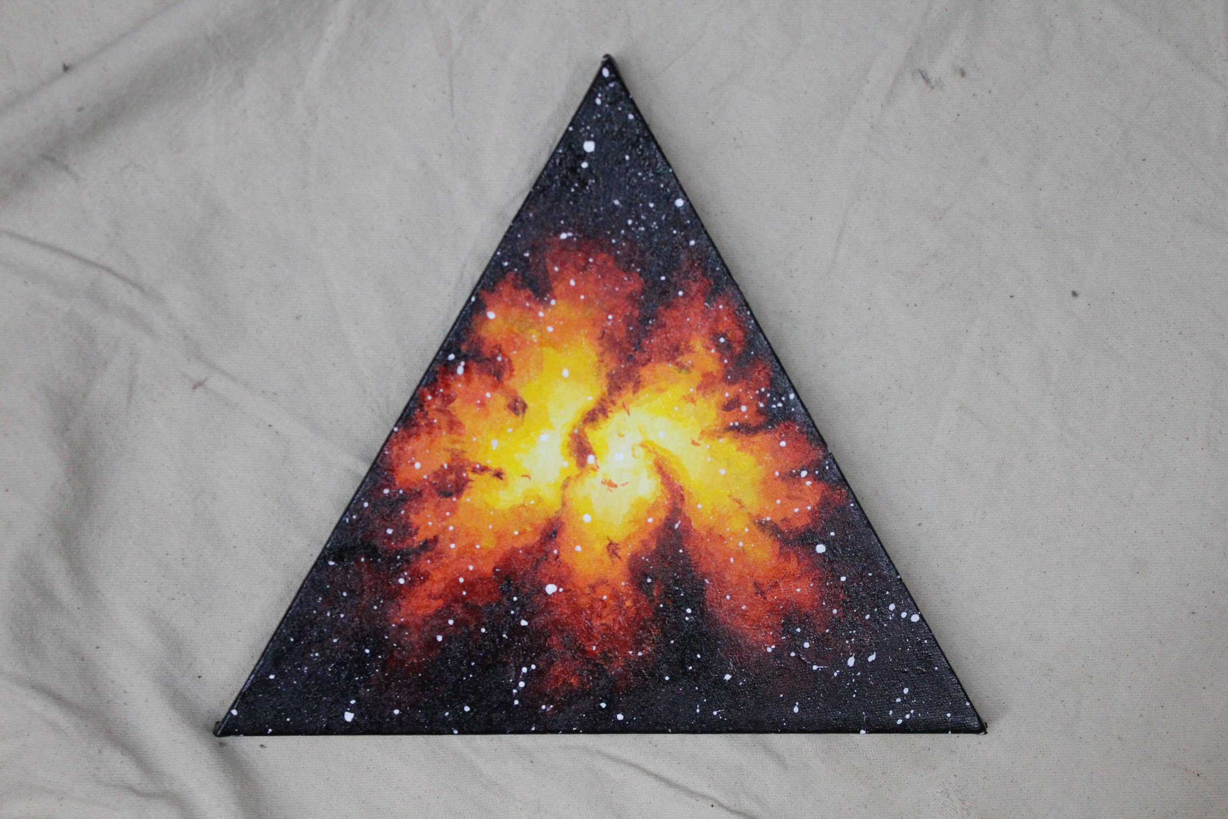 Painted triangle depicting a galaxy with bright yellow, orange, and red colors against a black background with white star splatters.