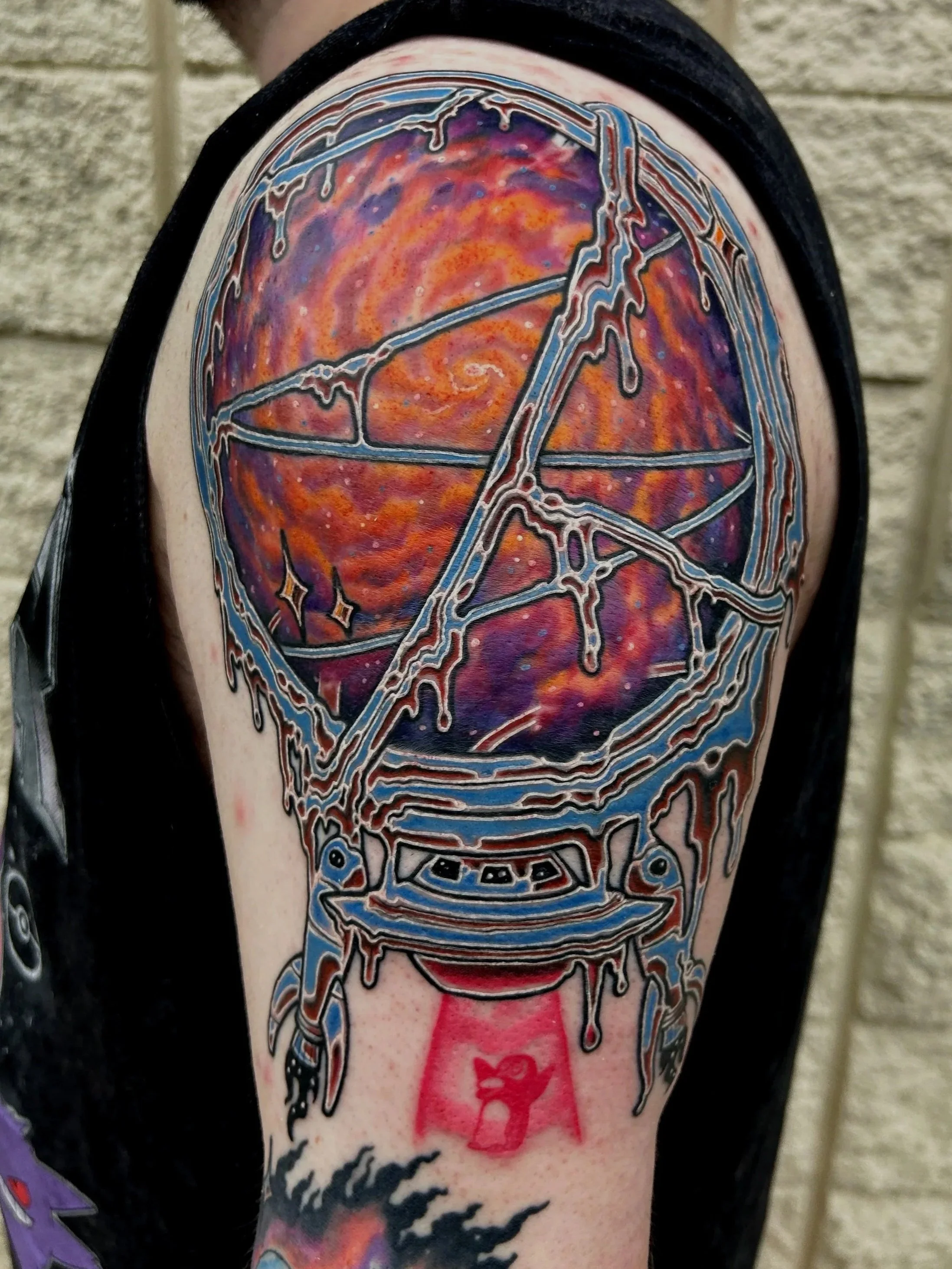 Colorful tattoo of a stylized chrome spaceship with a space-themed background on a person's arm.