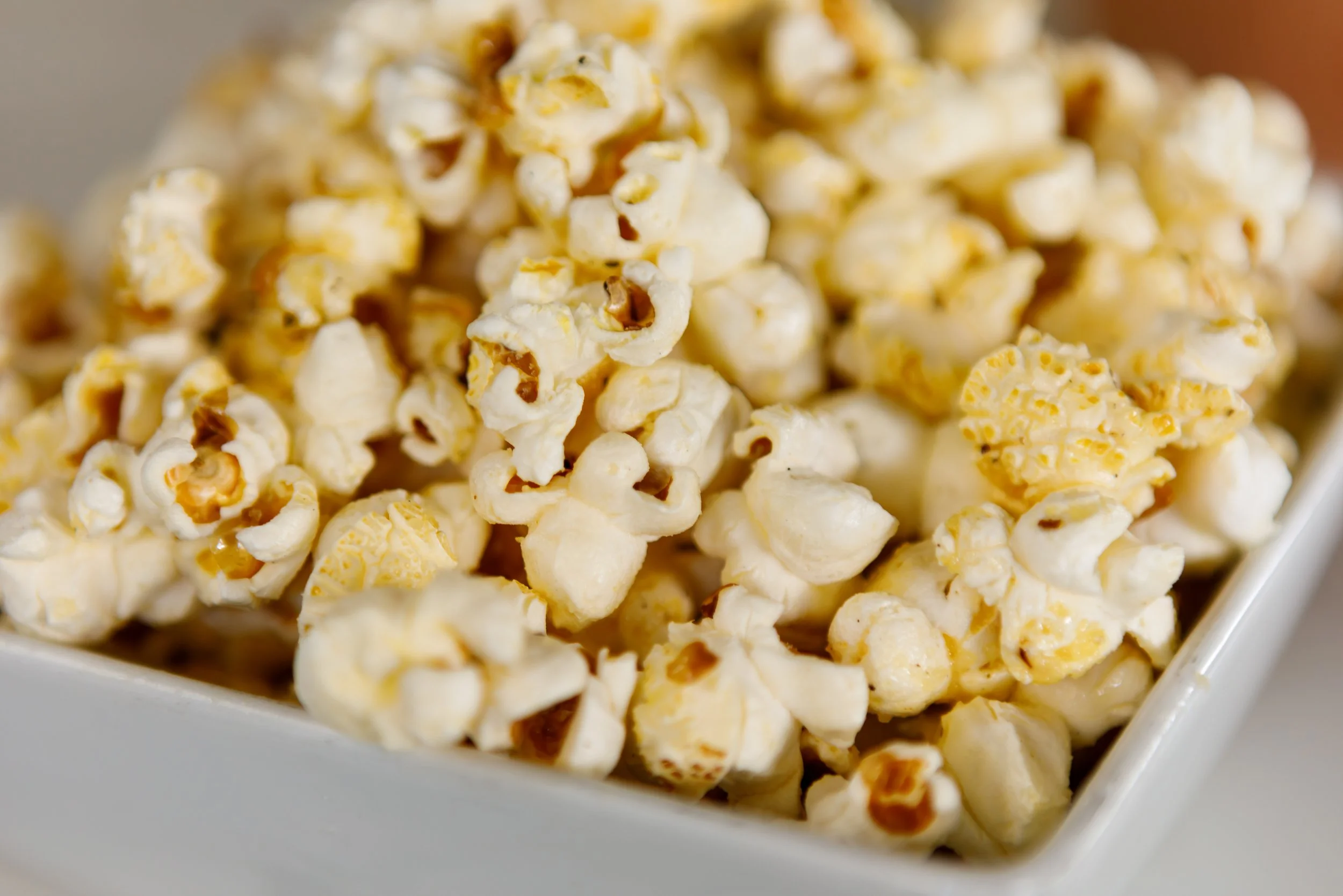 Close-up of a white bowl filled with freshly popped popcorn.