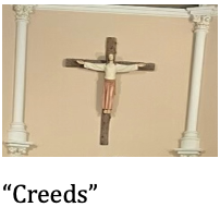 Wall crucifix with a figure of Jesus Christ, flanked by two white columns