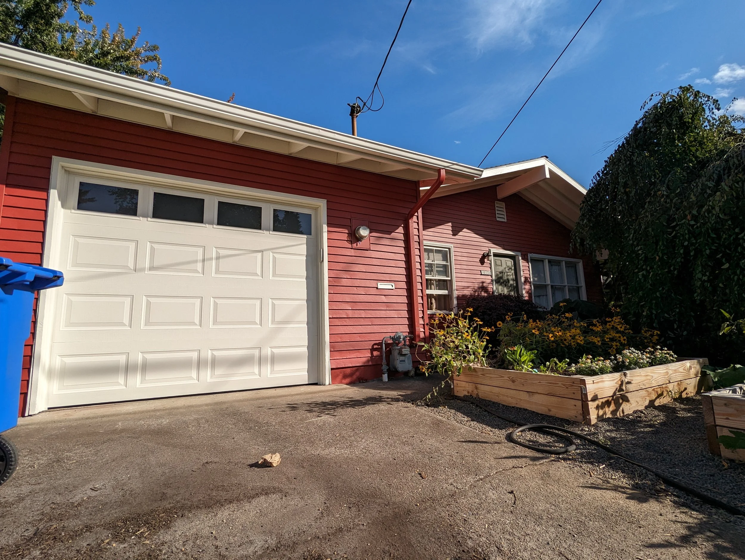 picture of a freshly painted red house with cream colored garage door